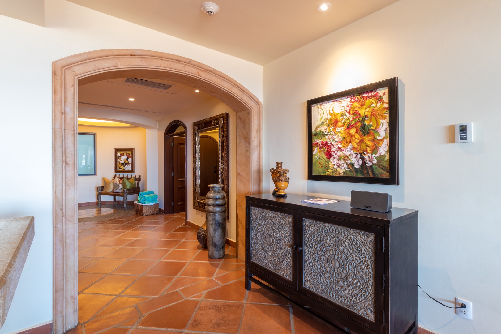 Step through the elegant arched doorway and feel at home in this welcoming entryway adorned with vibrant art, handcrafted décor, and warm terracotta tiles underfoot.