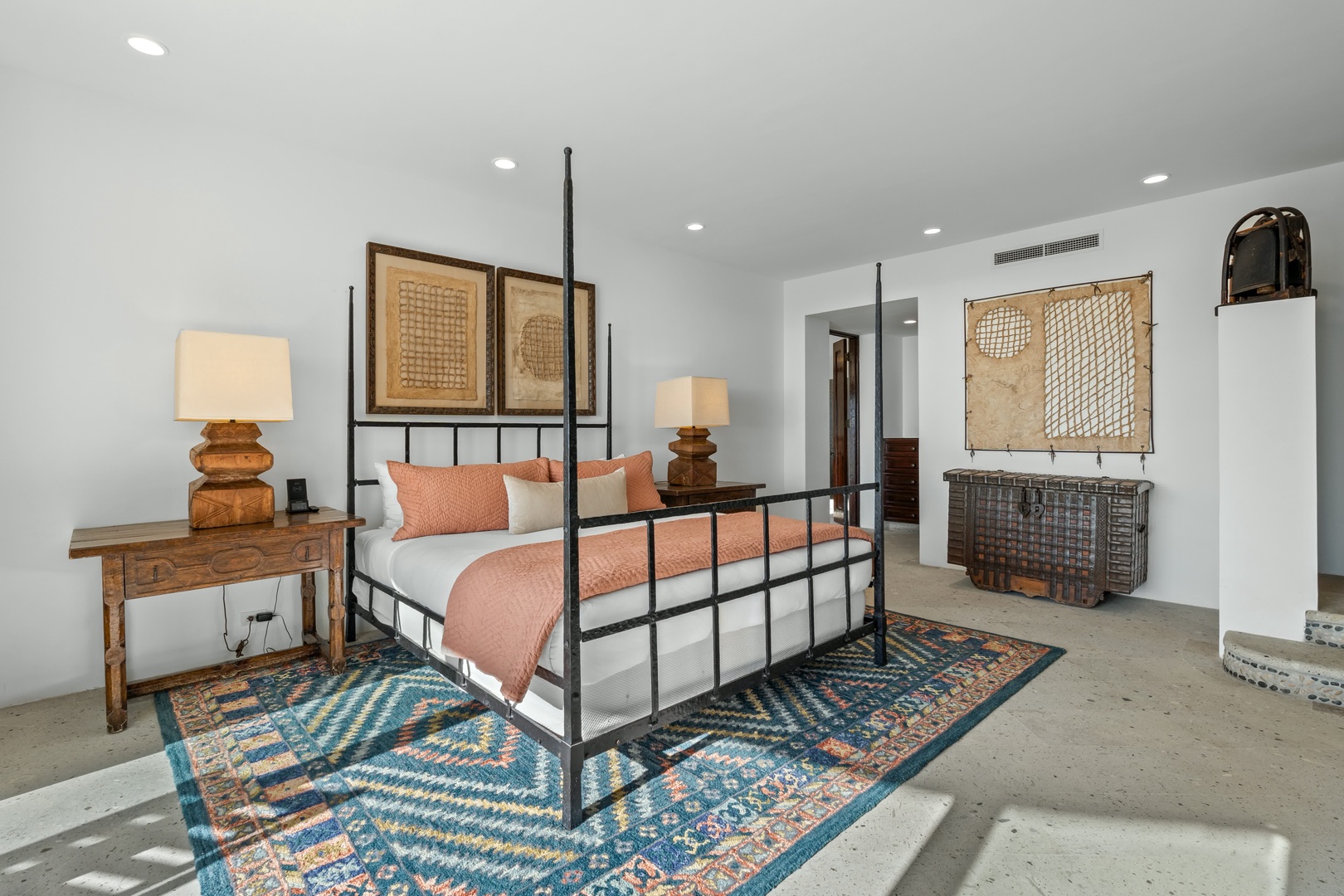Sink into the elegant four-poster bed surrounded by curated art and warm wood furnishings in your serene retreat.