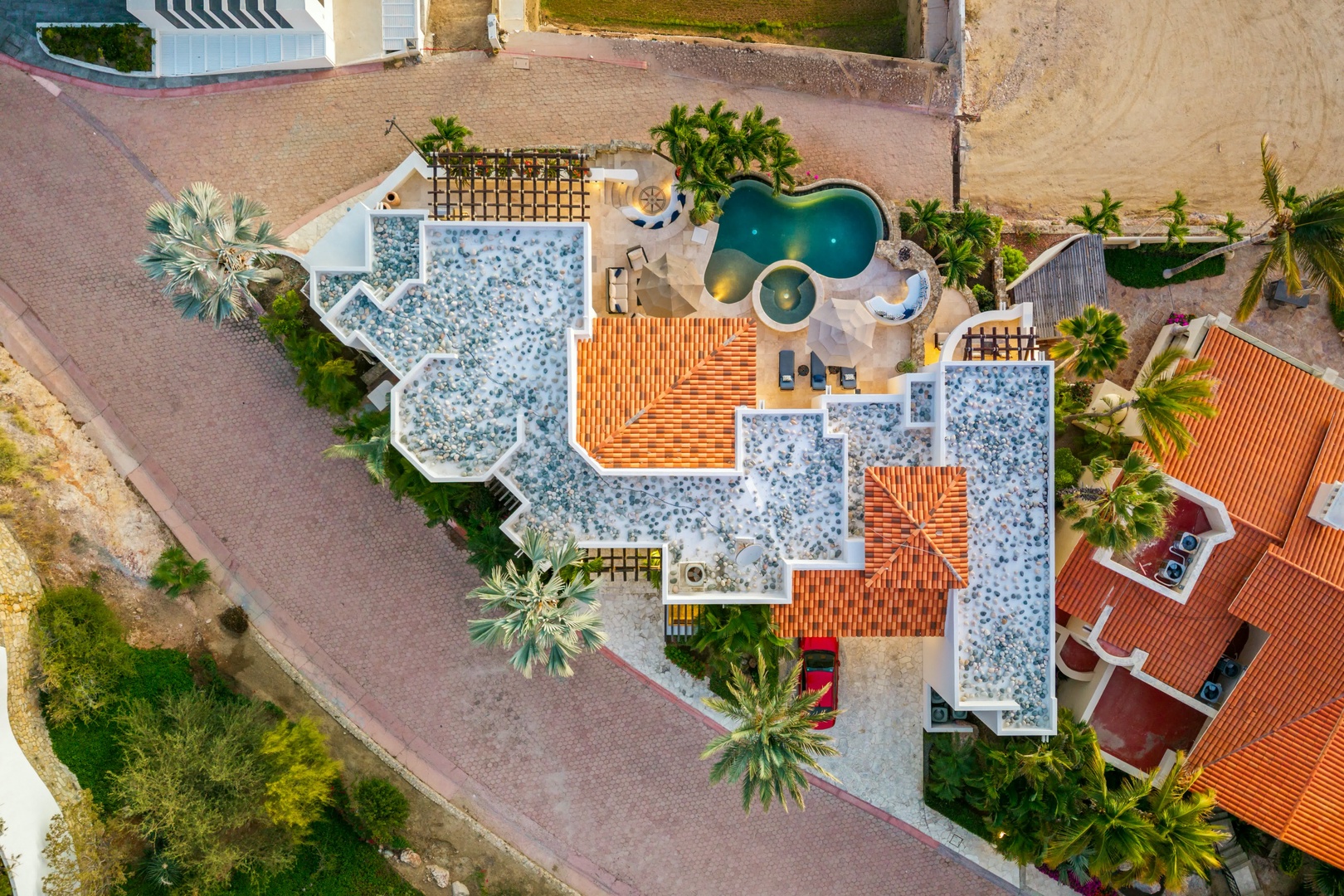 A stunning aerial perspective showcases this distinctive property with its unique architectural design, lush tropical landscaping, and sparkling pool area.