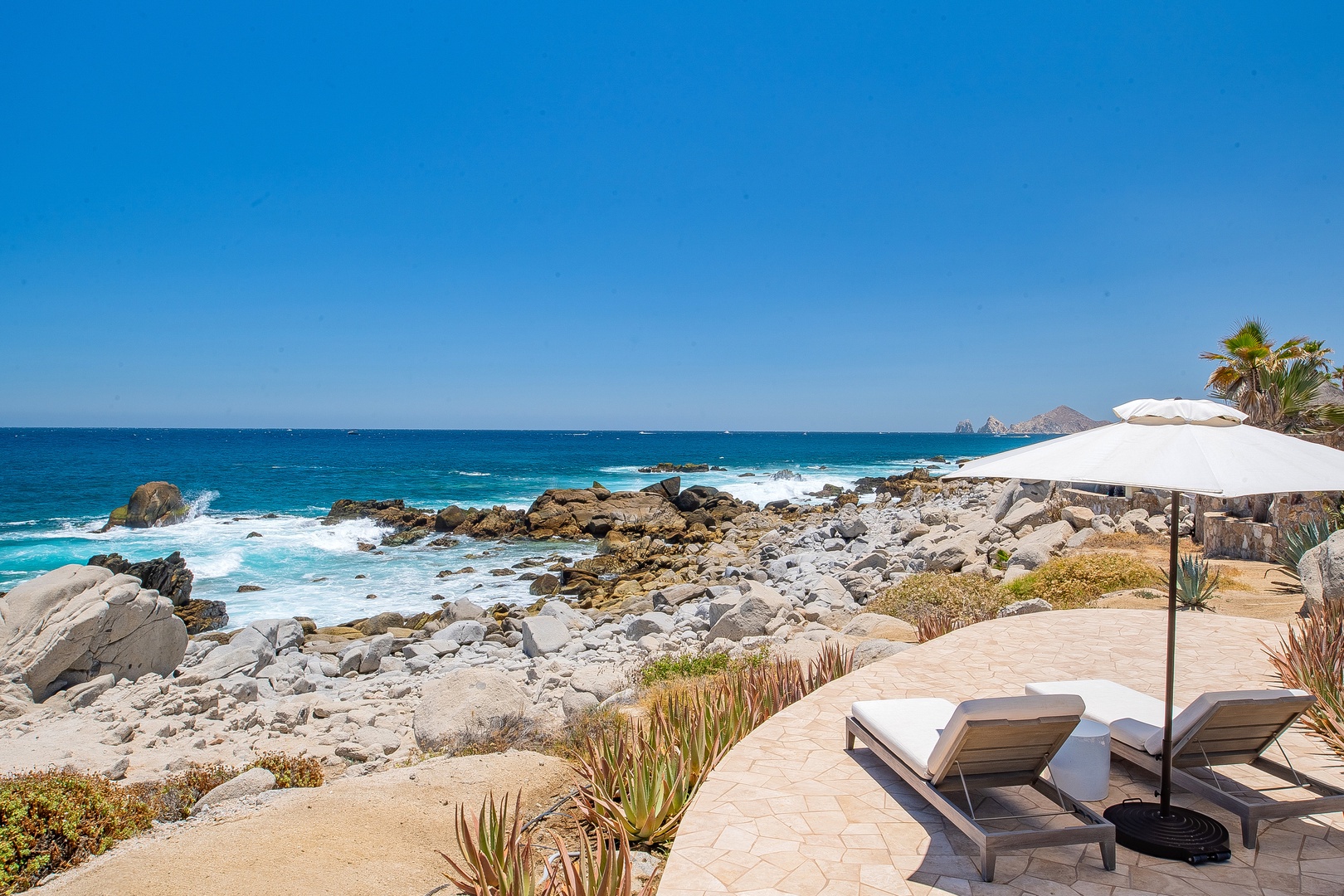 Unwind on your private oceanfront terrace where turquoise waves meet dramatic rocky shores, creating the perfect backdrop for pure relaxation.