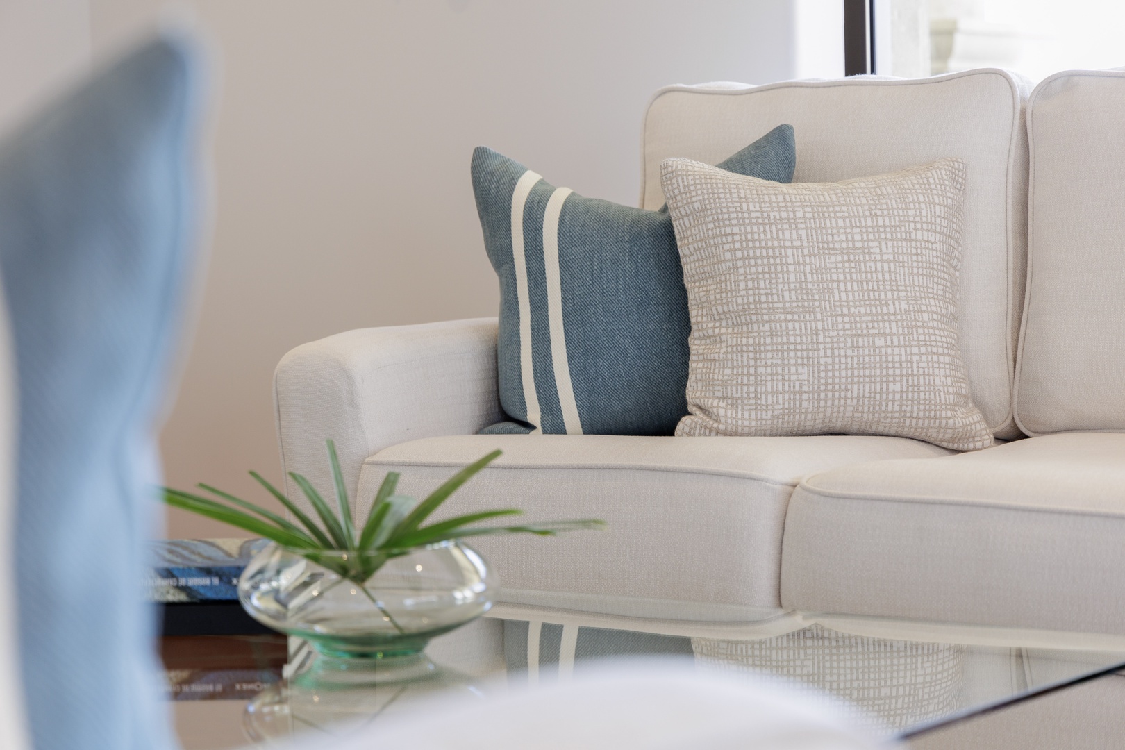 Sink into plush cushions and unwind in your elegant living space, where soothing coastal tones and thoughtful touches create the perfect spot for relaxation.