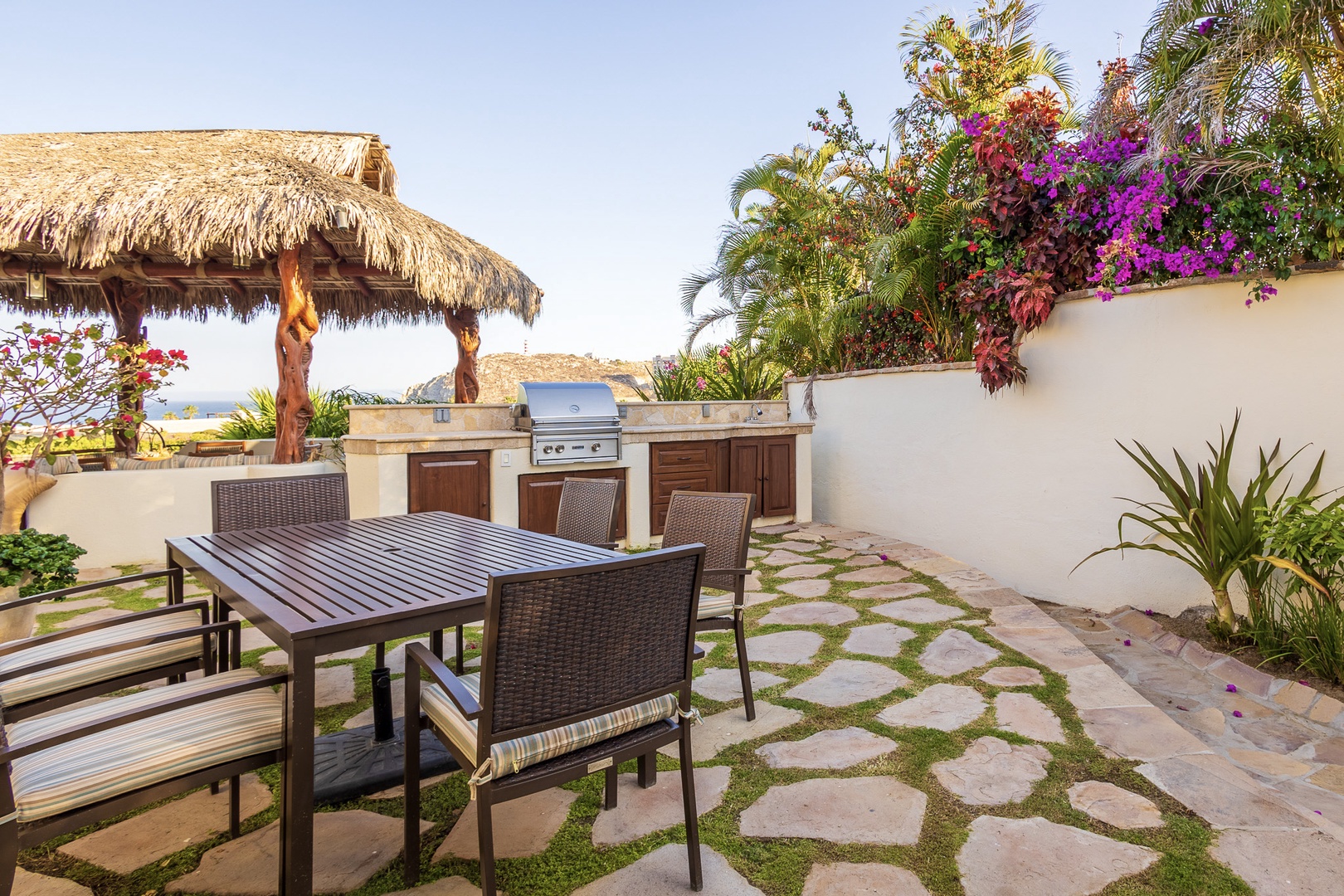 Your own private oasis awaits with an outdoor dining table, built-in BBQ, and thatched palapa—perfect for grilling and gathering under tropical blooms and ocean breezes.