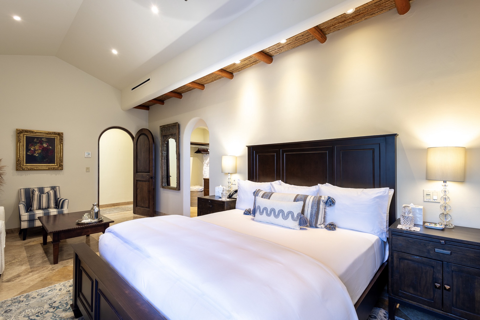 Sink into plush white linens beneath rustic exposed beams in your private retreat, where timeless elegance meets modern comfort in every thoughtful detail.