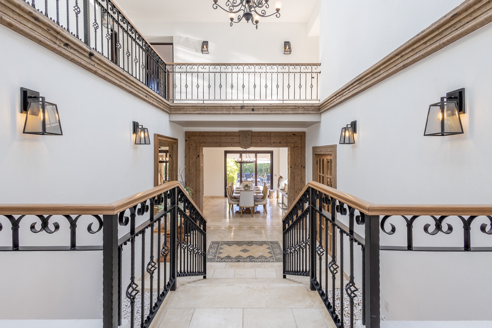 Step into a stunning two-story entryway where elegant wrought-iron railings and warm wood accents welcome you home. Natural light flows through to a gracious dining area beyond, setting the tone for your stay.