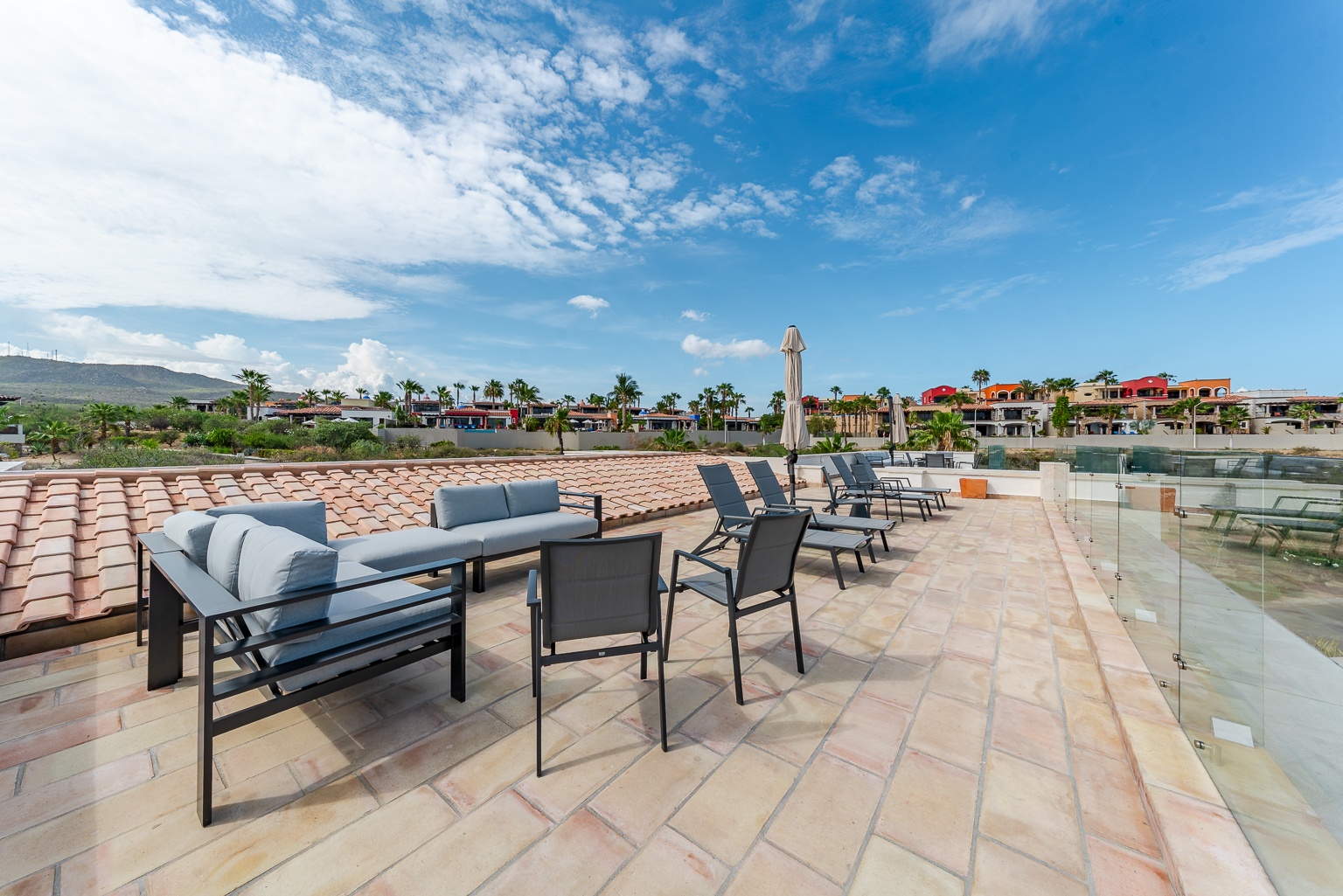 Expansive rooftop terrace offering open-air lounging with mountain and neighborhood views, complete with comfortable seating arrangements for outdoor relaxation and entertaining.