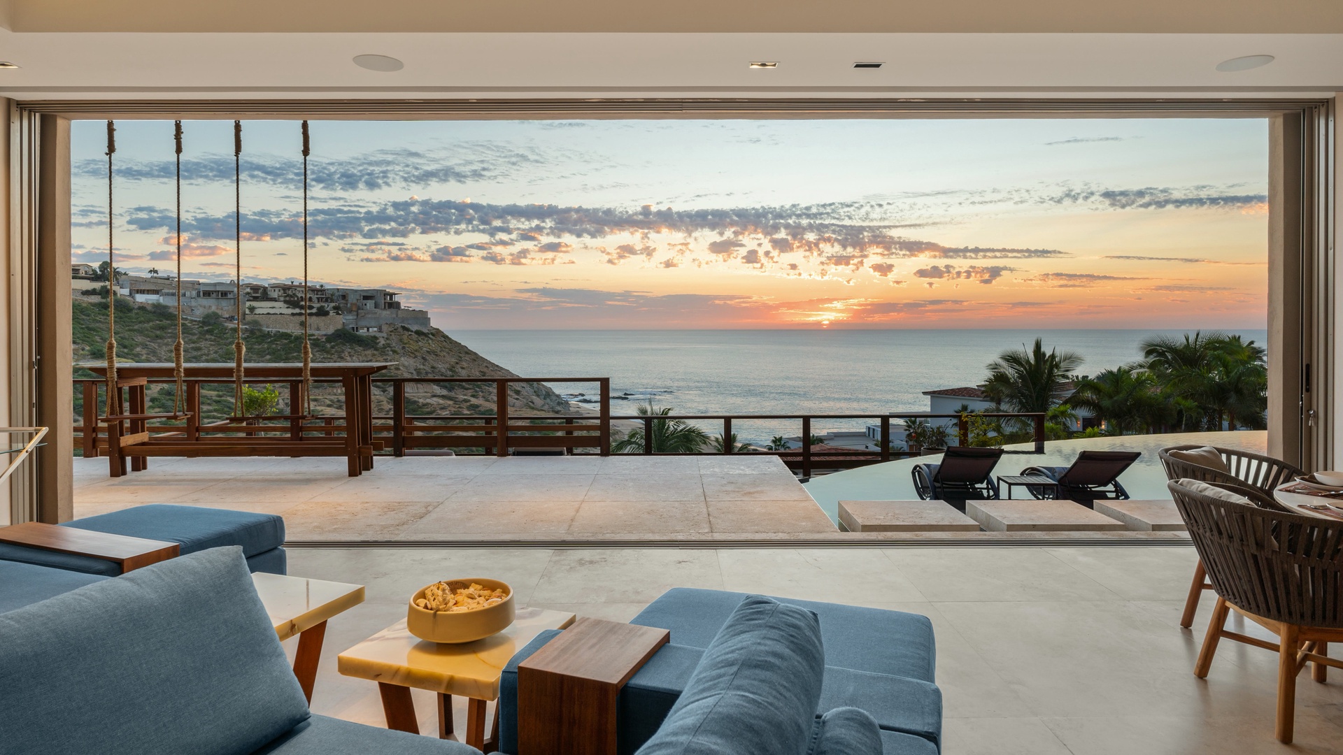Stunning coastal property featuring infinity pool and sweeping ocean views at sunset. This modern cliffside retreat offers seamless indoor-outdoor living with spacious terrace overlooking the sea.