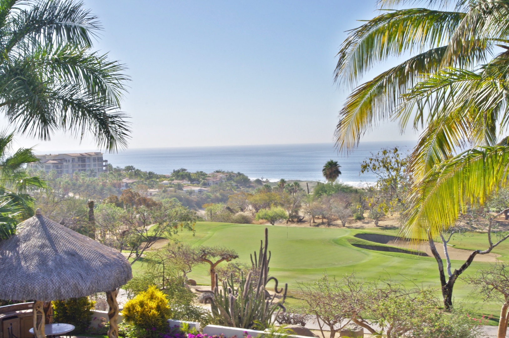 Sweeping views showcase lush golf course greens, tropical palm trees, and sparkling ocean waters beyond—a scenic backdrop framing the property's tranquil coastal setting.