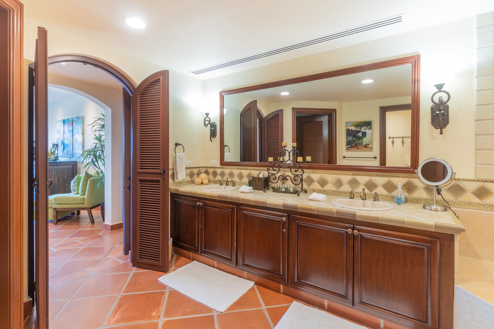 Step into your elegant en-suite bathroom with dual vanities, warm terracotta tile floors, and rich wood cabinetry that invites relaxation and comfort.