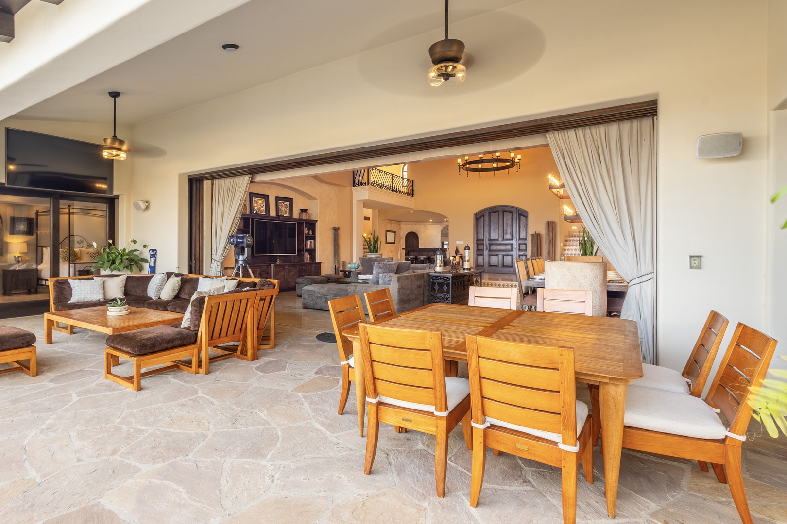 Your covered patio seamlessly blends indoor comfort with outdoor charm, featuring warm wood dining and lounging areas that flow into the elegant living space beyond.