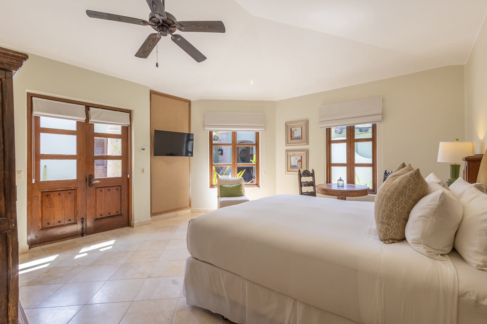 Your spacious bedroom offers comfort with crisp linens, gentle ceiling fan breezes, and warm natural light streaming through beautiful wooden windows.