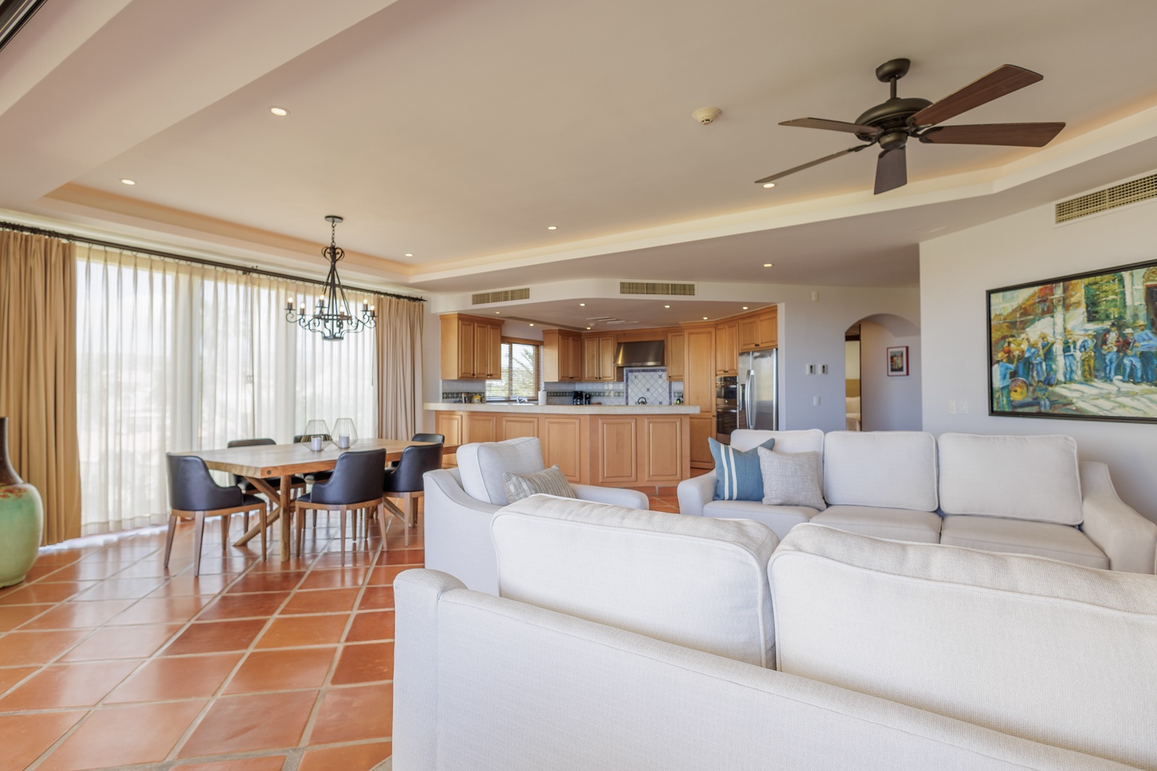 Sink into plush sofas in this sun-soaked open living space, where vaulted ceilings and terracotta floors create a warm, elegant retreat. Gather at the dining table or whip up meals in your gourmet kitchen.