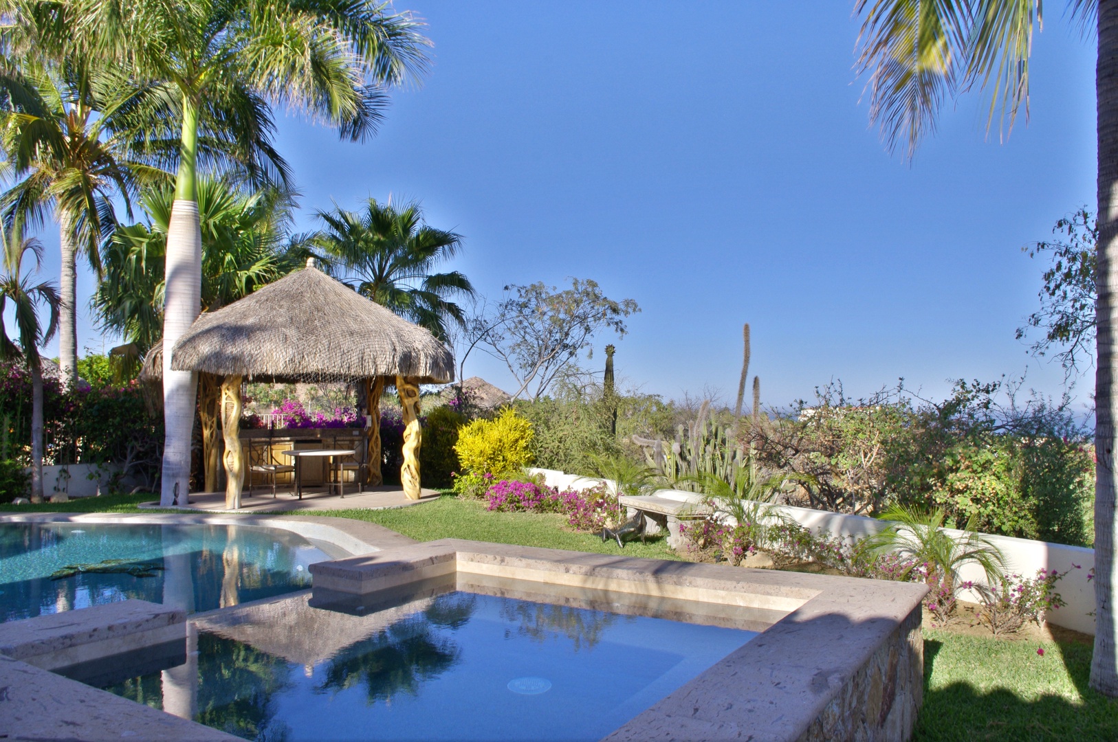 A tropical oasis awaits in this beautiful backyard. Lounge by the sparkling pool, relax under the thatched palapa, and soak in stunning desert-meets-ocean views. Pure paradise.