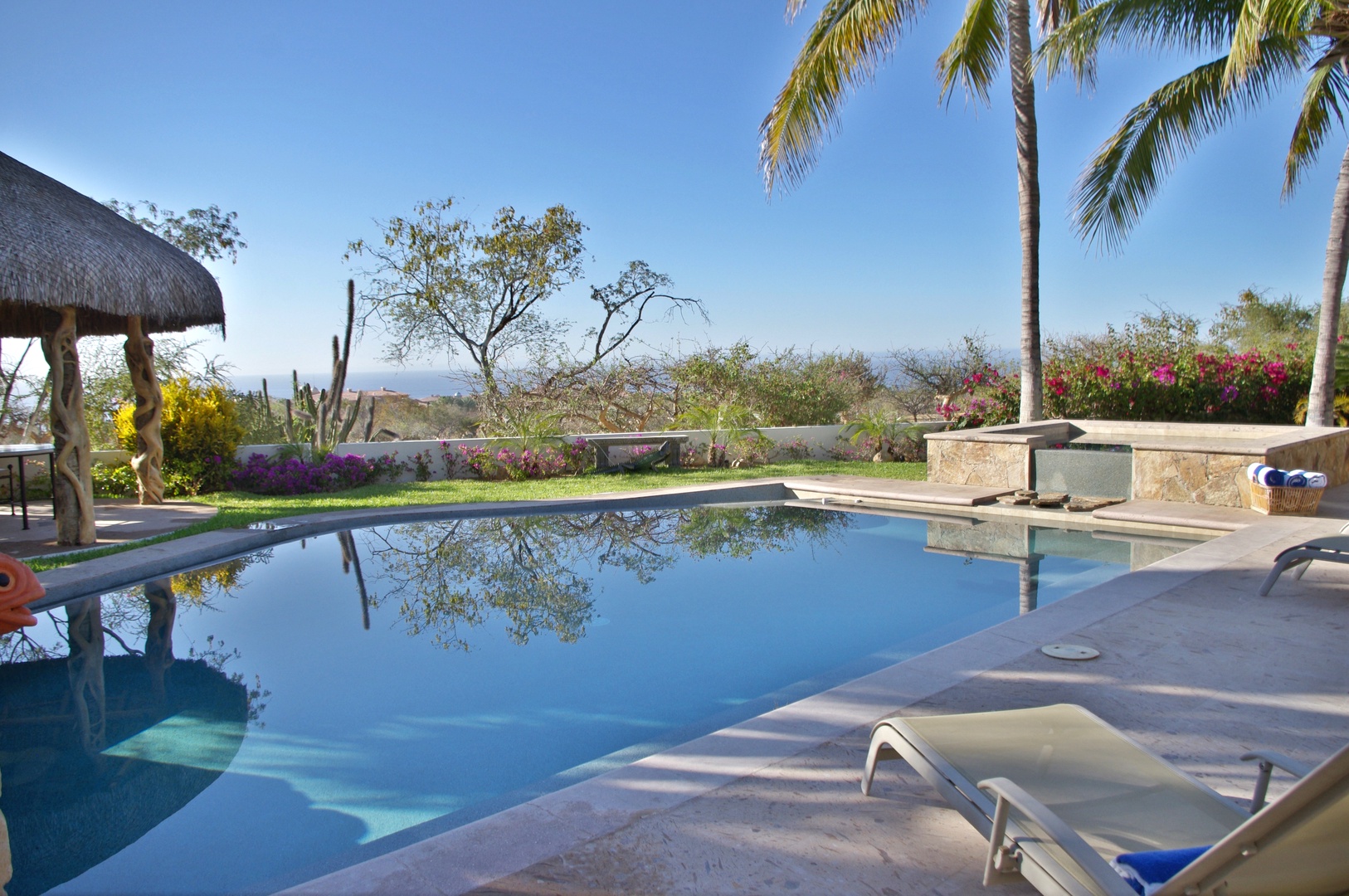 Soak in your private pool surrounded by tropical palms and colorful gardens, with serene ocean views stretching beyond. A perfect retreat to unwind under the sun.