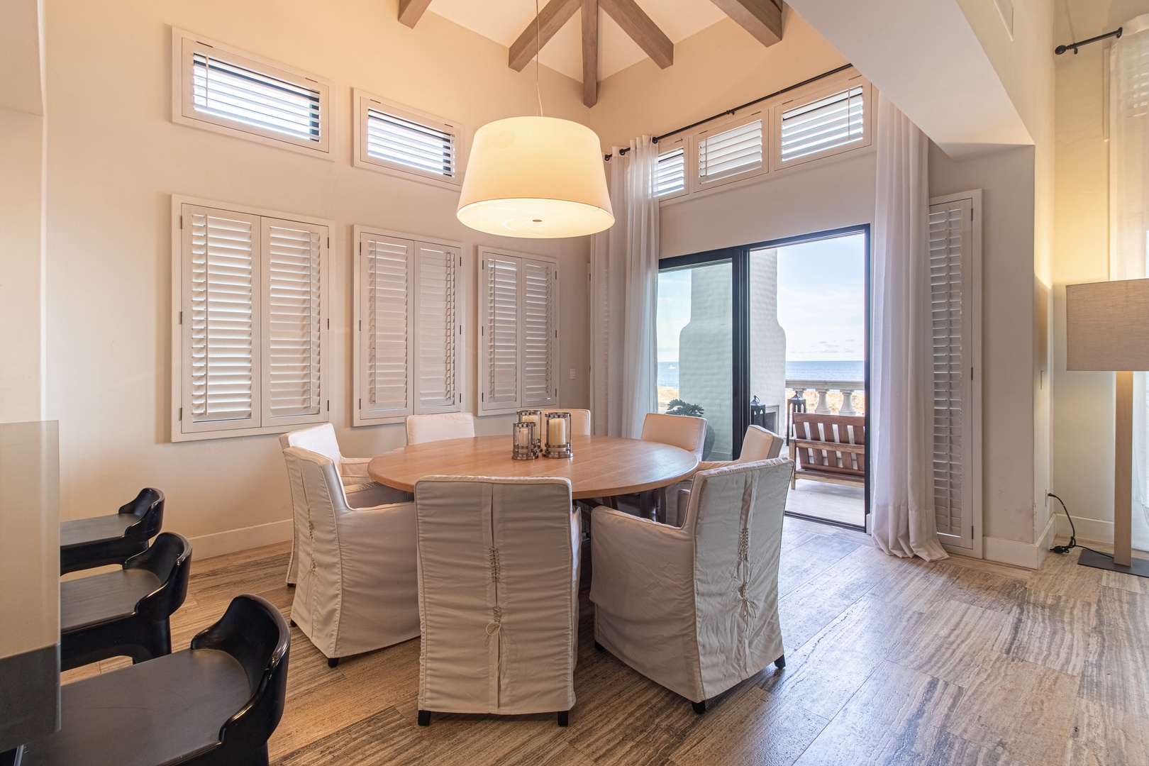 Gather around this warm dining space where elegant beams frame your meals and ocean breezes drift through the balcony doors, inviting you to linger over conversation.