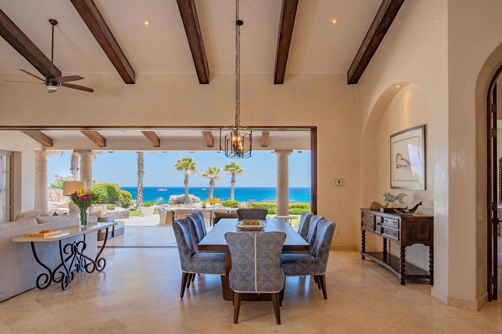 Enjoy elegant dining under exposed beam ceilings while gazing at stunning ocean views through expansive windows.