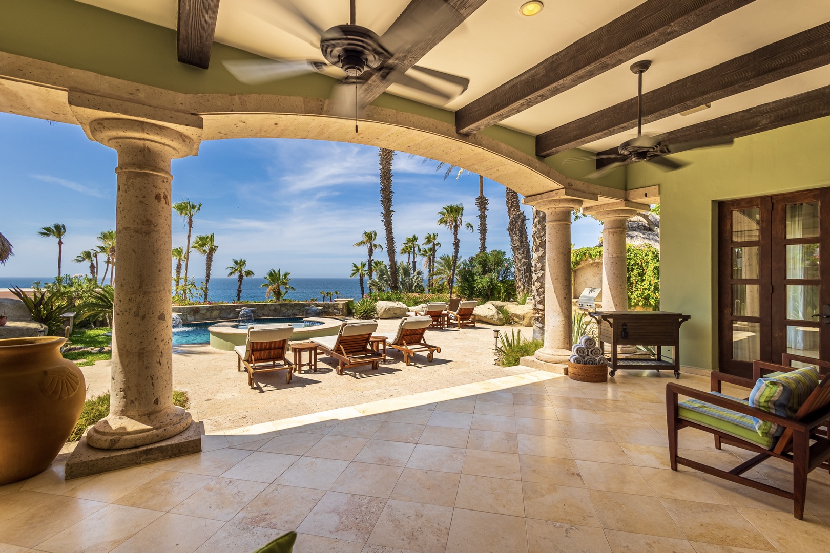 Relax under your private covered terrace with stunning ocean views, elegant columns, and poolside comfort in paradise.