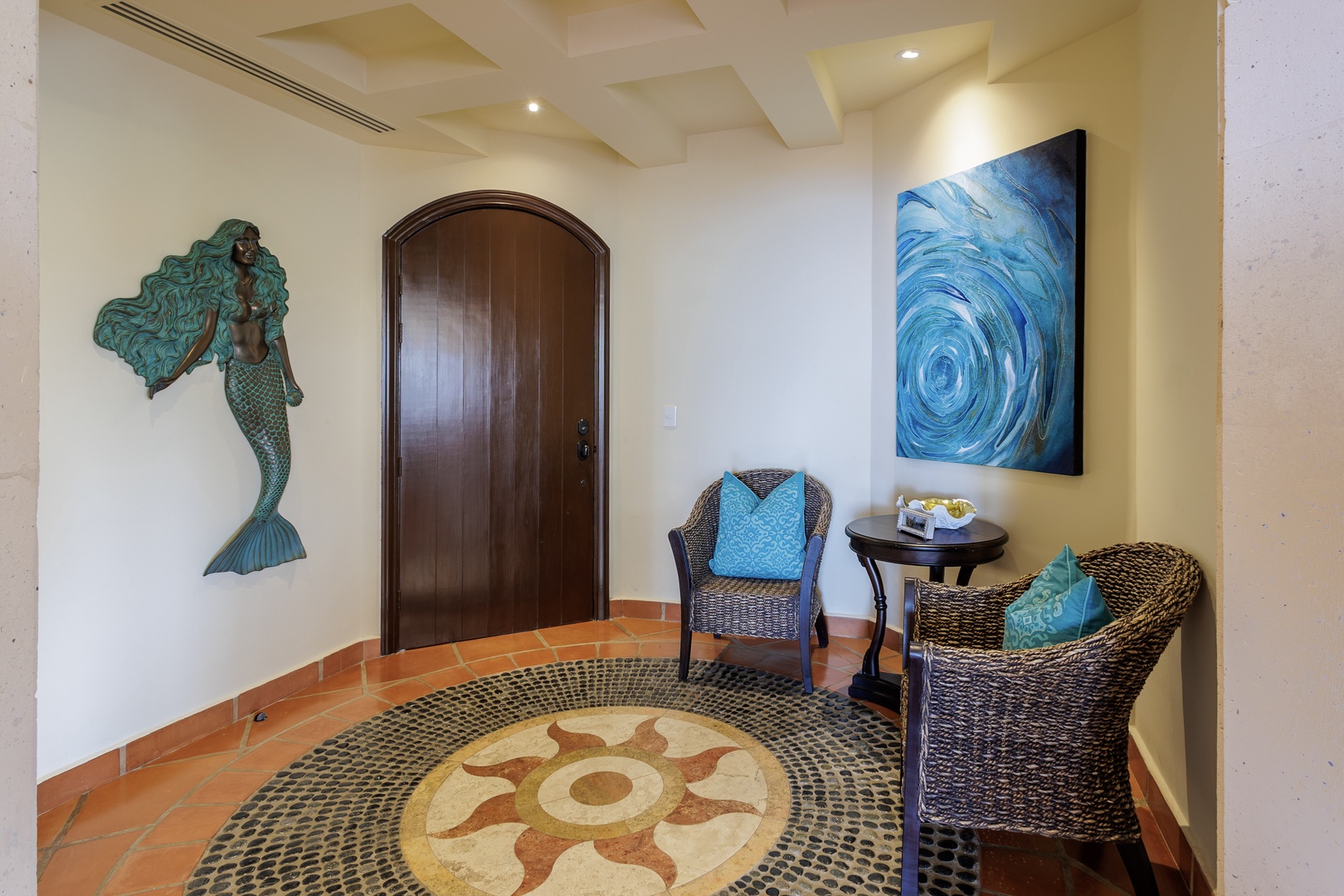 Welcome to your coastal retreat, where a charming entryway greets you with whimsical mermaid art and ocean-inspired touches. Sink into cozy wicker seating beneath swirling blue artwork that captures seaside serenity.