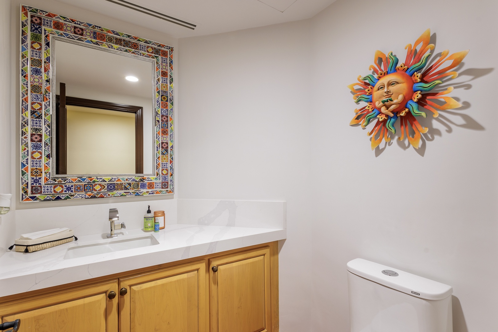 Your bathroom features vibrant artistic touches, a clean vanity with essentials at hand, and thoughtful storage beneath to keep your space tidy and comfortable.