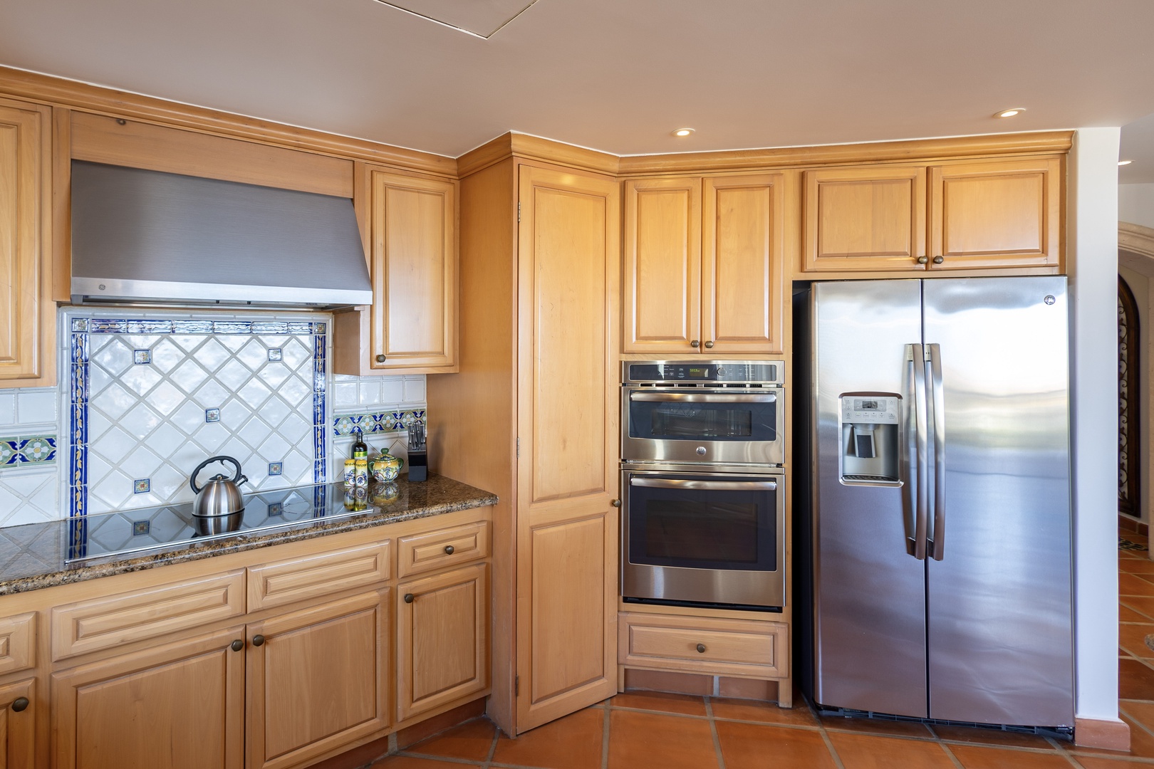 This fully equipped kitchen features rich wood cabinetry, stainless steel appliances, and charming tile details—perfect for preparing your favorite meals during your stay.