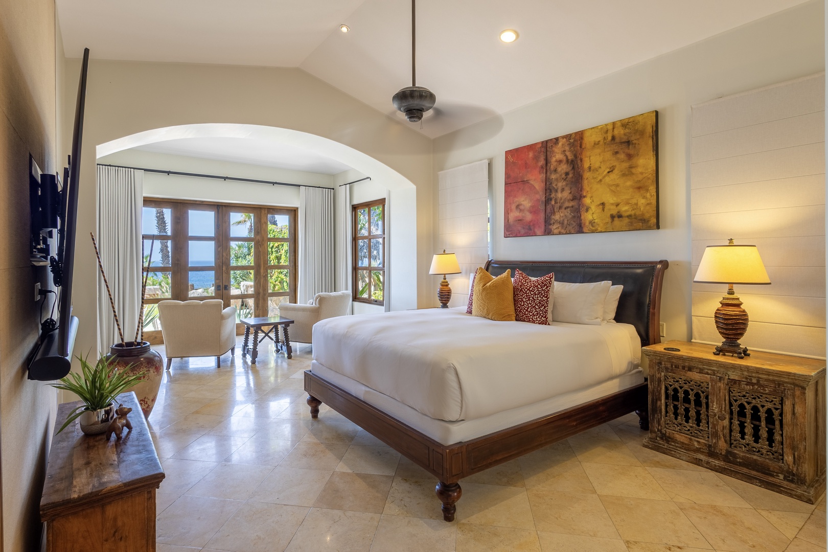 Unwind in your elegant master suite with luxurious bedding, warm ambient lighting, and a cozy seating area overlooking tropical gardens.