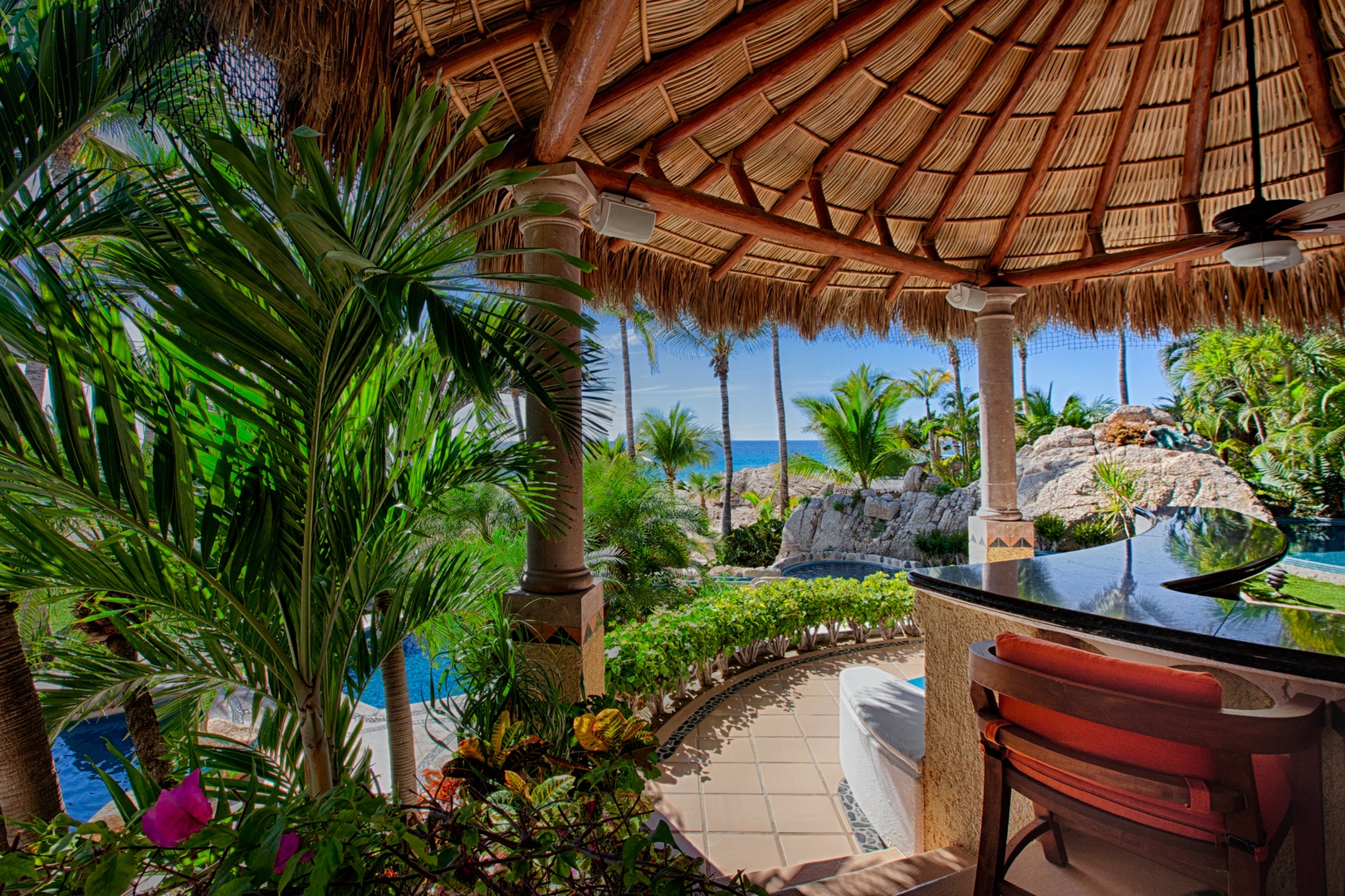 Your private tropical terrace offers shade under thatched palapa while you enjoy ocean views through swaying palms.