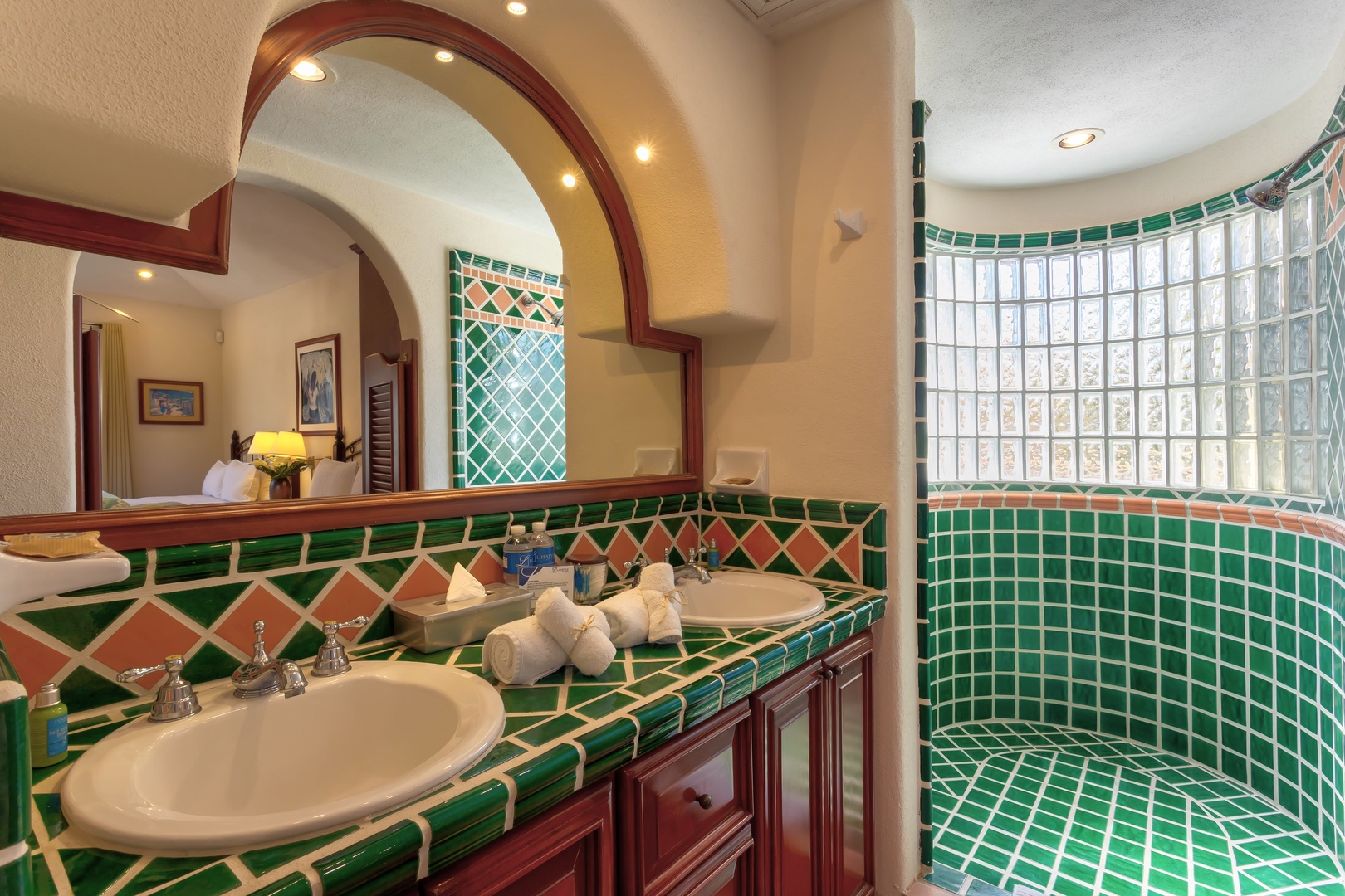 Step into your vibrant tiled bathroom featuring a stunning curved glass block shower and elegant dual vanities with warm wood cabinetry.