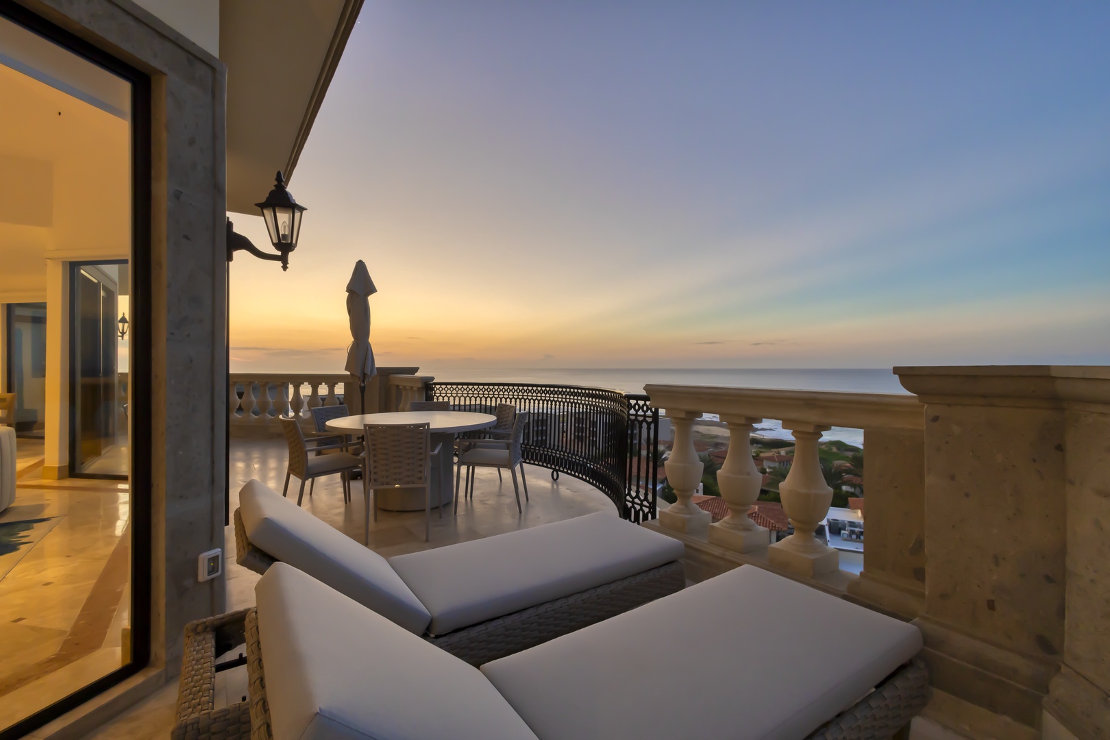 Elegant terrace with sea views at sunset, offering a tranquil space to unwind with comfortable loungers, dining seating, and panoramic coastal scenery at dusk.
