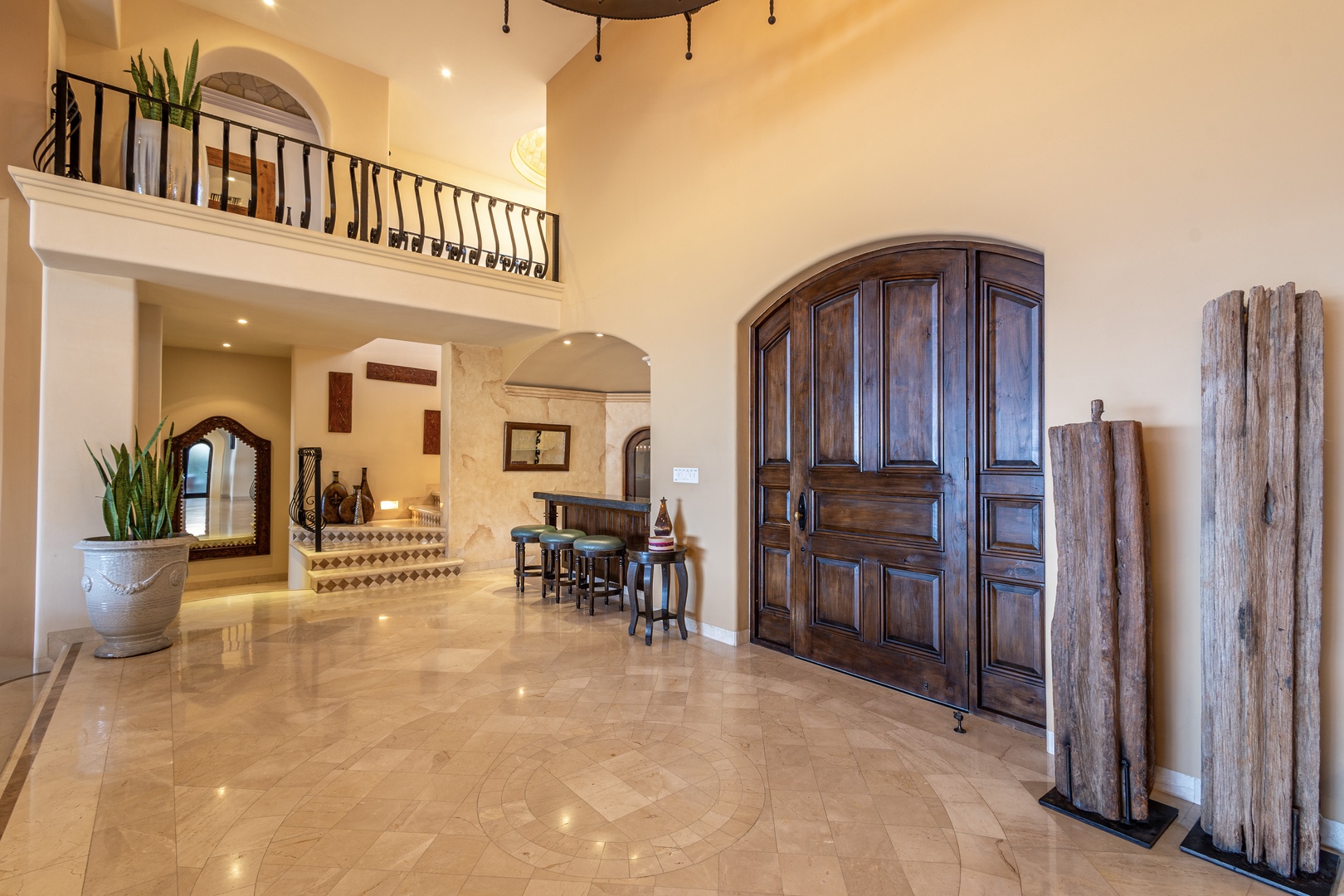 Step into this stunning Mediterranean-inspired entryway, where soaring ceilings and elegant arches welcome you home. Gleaming tile floors, rich wood accents, and an open layout create a warm, sophisticated atmosphere perfect for your getaway.