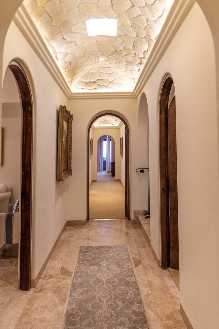 Step through hand-carved wooden archways beneath an artfully crafted stone ceiling, where elegant simplicity meets timeless Mediterranean charm in your private hallway.
