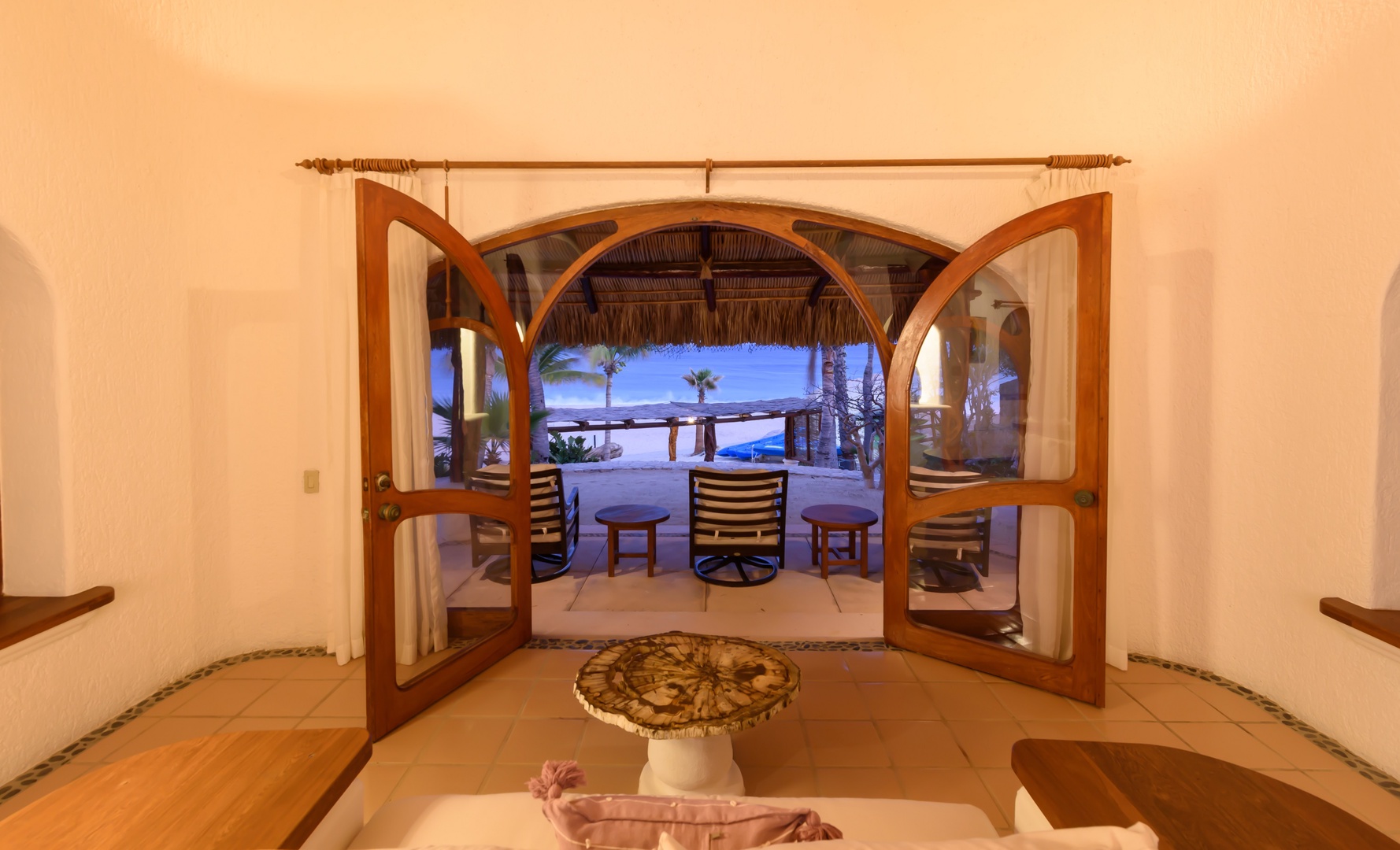This inviting entrance frames a stunning beachfront paradise just steps away, where ocean breezes and tropical palms await your arrival at this coastal retreat.
