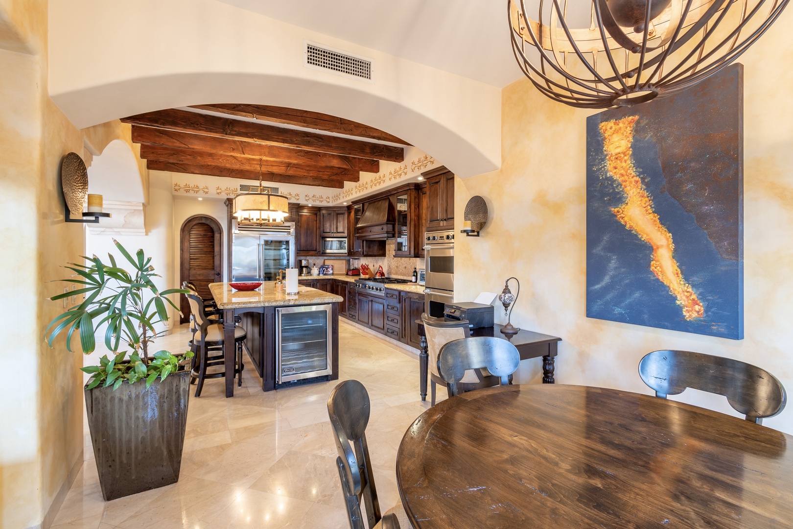 Picture yourself preparing meals in this spacious chef's kitchen with rich wood cabinetry and modern appliances, then gathering at the handsome dining table under artistic lighting for memorable dinners together.