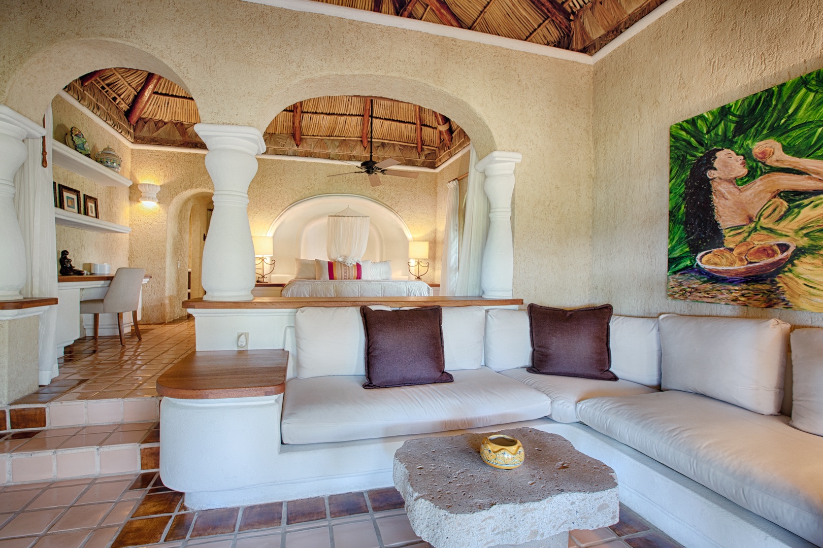 Relax in your stunning villa featuring dramatic arched architecture, plush sectional seating, and vibrant local artwork creating an authentic tropical paradise.