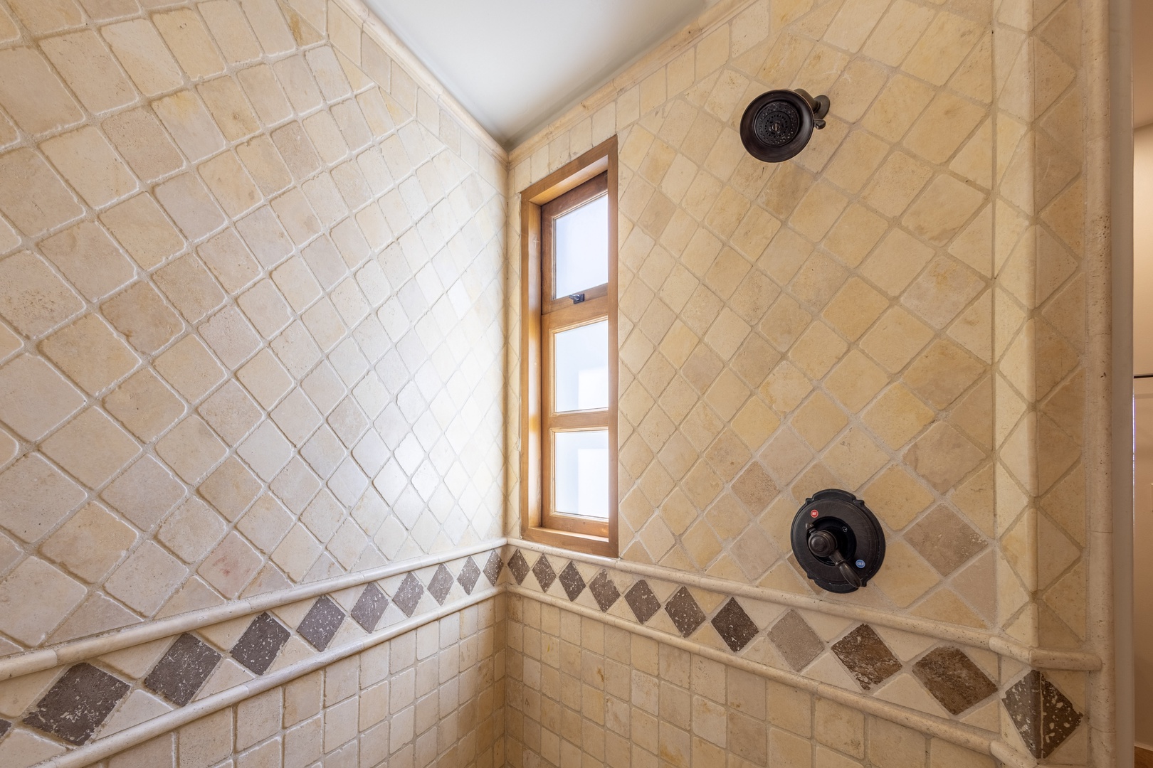Your luxurious tiled shower features elegant stone work and diamond accents, creating a spa-like retreat for your daily routine.