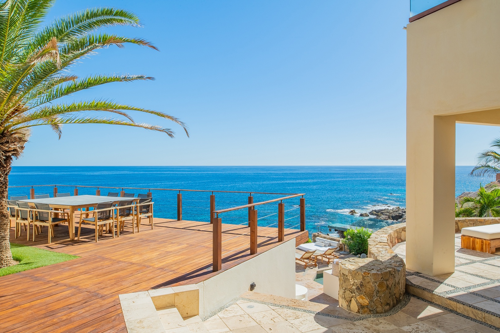 A stunning oceanfront terrace overlooks sparkling turquoise waters, framed by swaying palms and warm sunshine. The perfect spot for peaceful mornings or sunset gatherings.