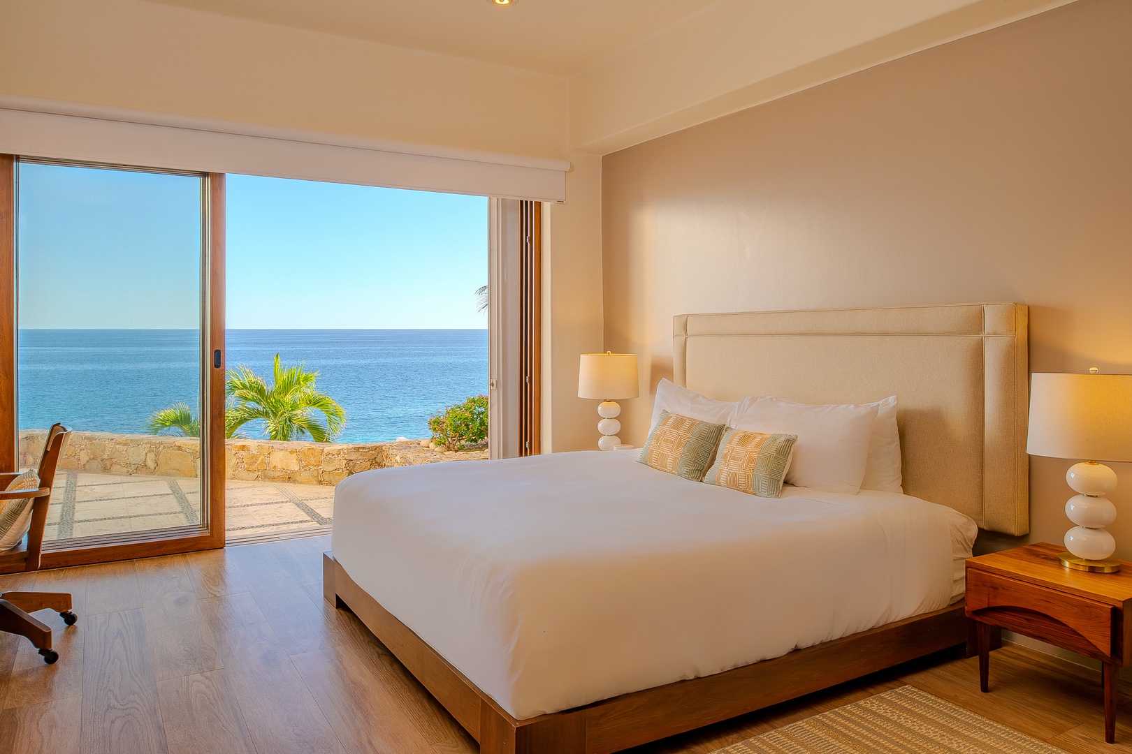 Wake up to breathtaking ocean views from your serene bedroom, where floor-to-ceiling windows frame the endless blue horizon and tropical palms sway just beyond your private terrace.