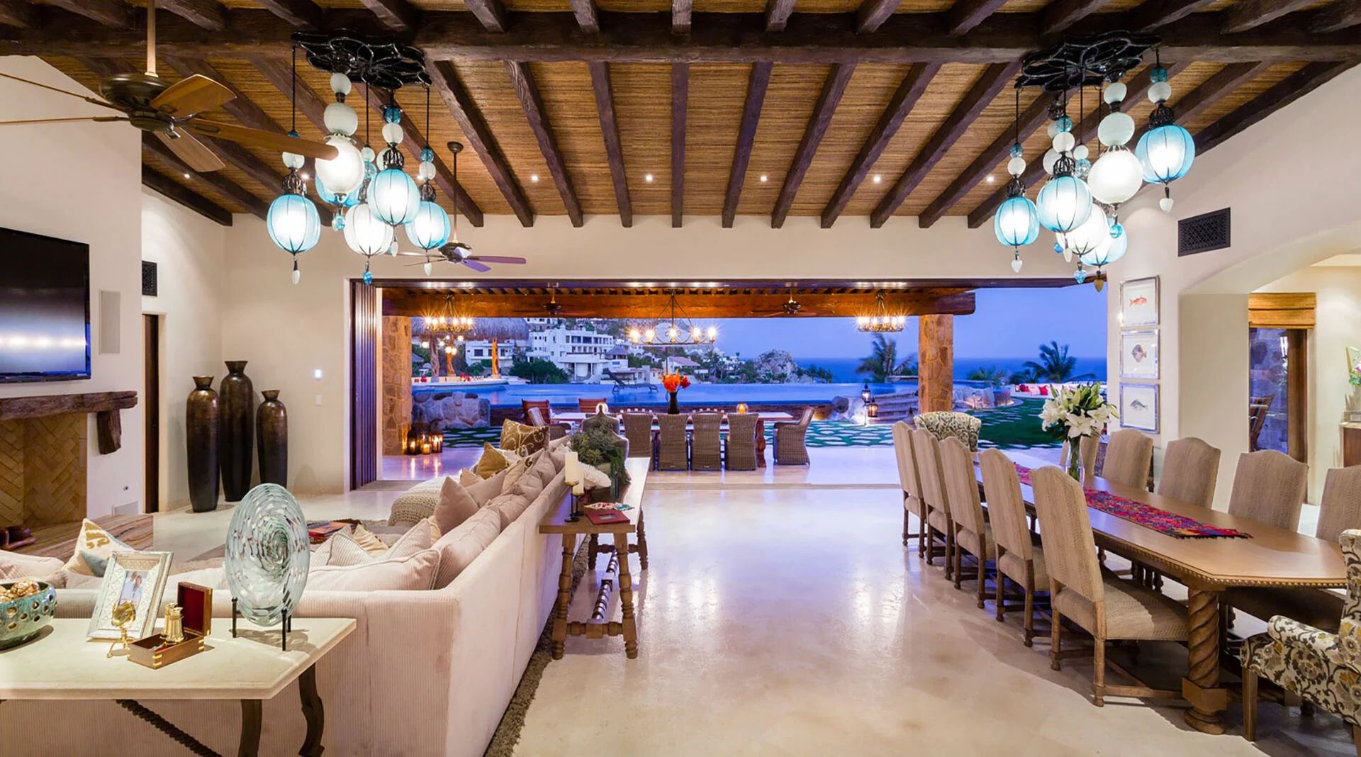 Expansive living and dining area framed by stunning exposed beams. Your gathering space opens seamlessly to twilight ocean views and inviting outdoor terraces—perfect for memorable evenings.