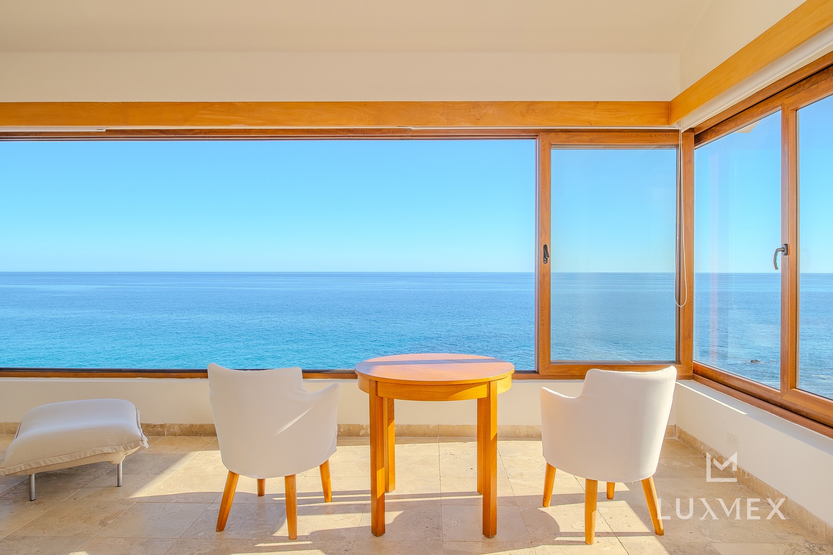 Your private dining nook frames endless ocean views through floor-to-ceiling windows, where morning coffee meets the horizon.