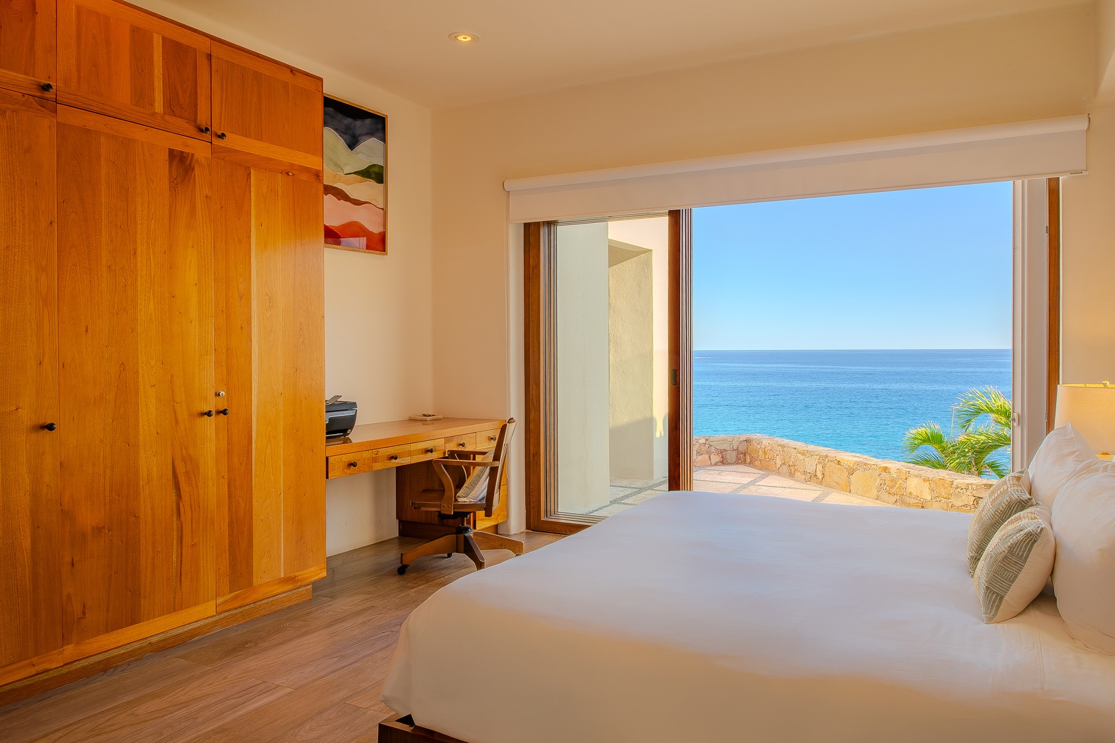 Wake up to sweeping ocean views from your plush bed, with a peaceful workspace and warm wooden details creating your serene seaside sanctuary.