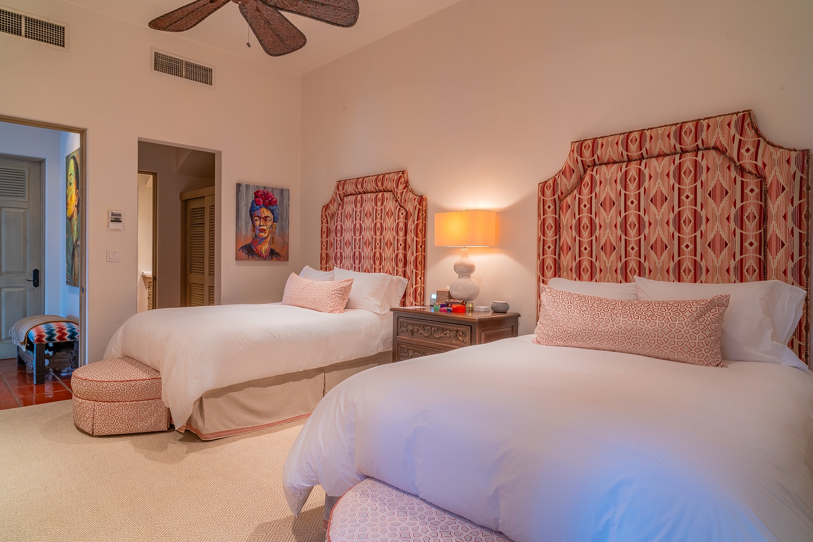 Unwind in this spacious bedroom with twin beds dressed in crisp linens and upholstered headboards, where a ceiling fan ensures your comfort year-round.