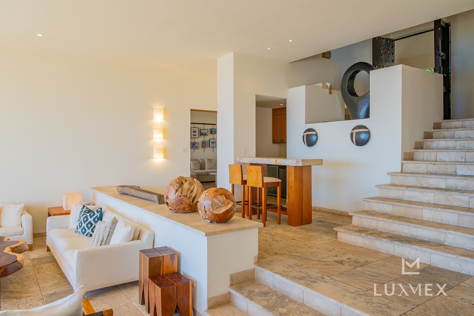 Relax in your sophisticated open-plan living space with sculptural decor and warm wood accents creating an artistic, contemporary atmosphere.