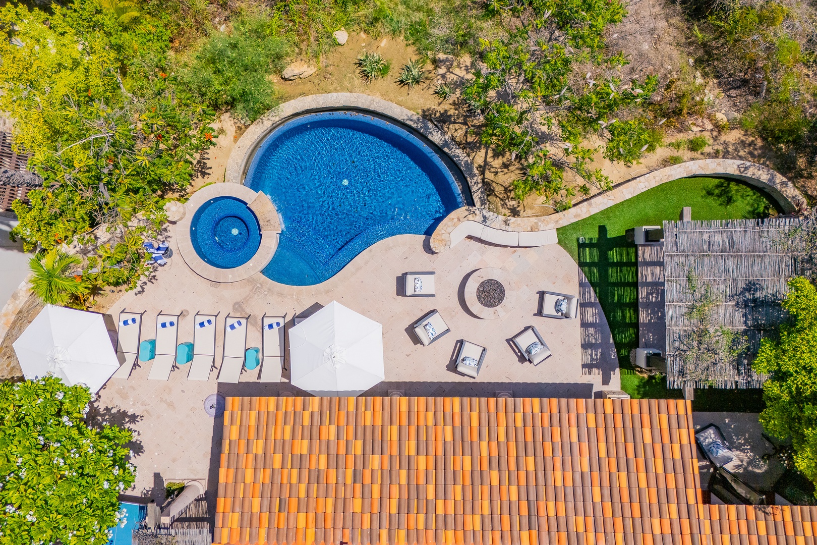 Aerial view of the property's resort-style pool complex, complete with a circular splash pool, sunbeds, and lush Mediterranean gardens—an inviting outdoor retreat.