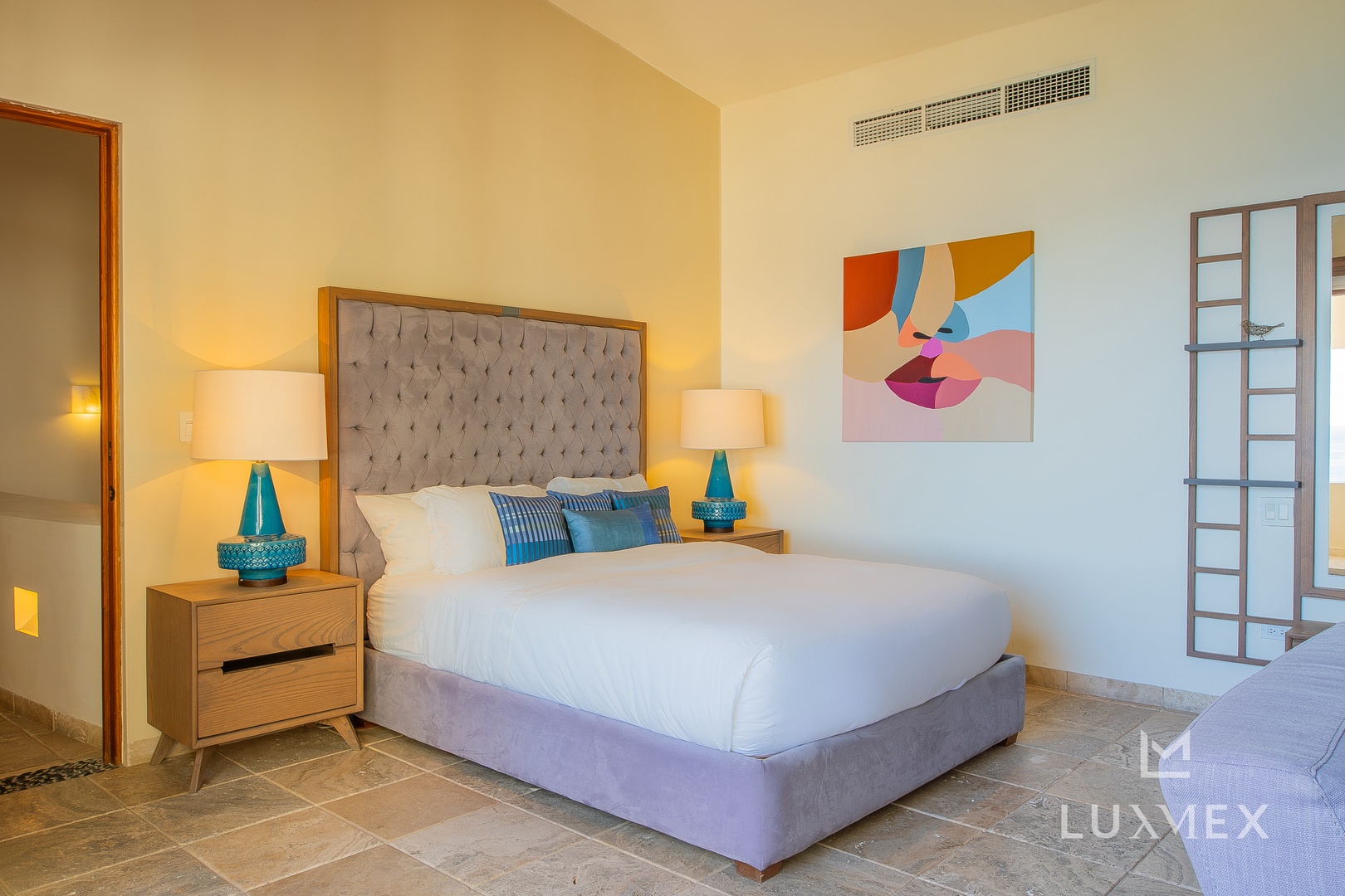 Sink into luxury with your plush tufted headboard and colorful artwork creating the perfect retreat for restful nights.