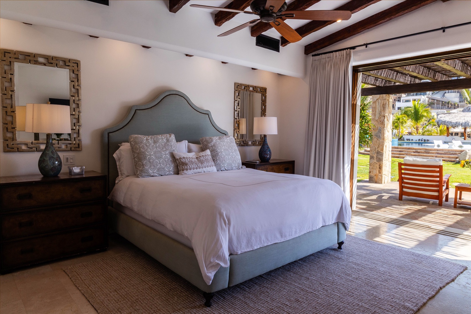 Step into your serene bedroom retreat where rustic wooden beams meet elegant comfort. Crisp linens invite restful sleep while your private terrace beckons with pool views and warm sunshine.