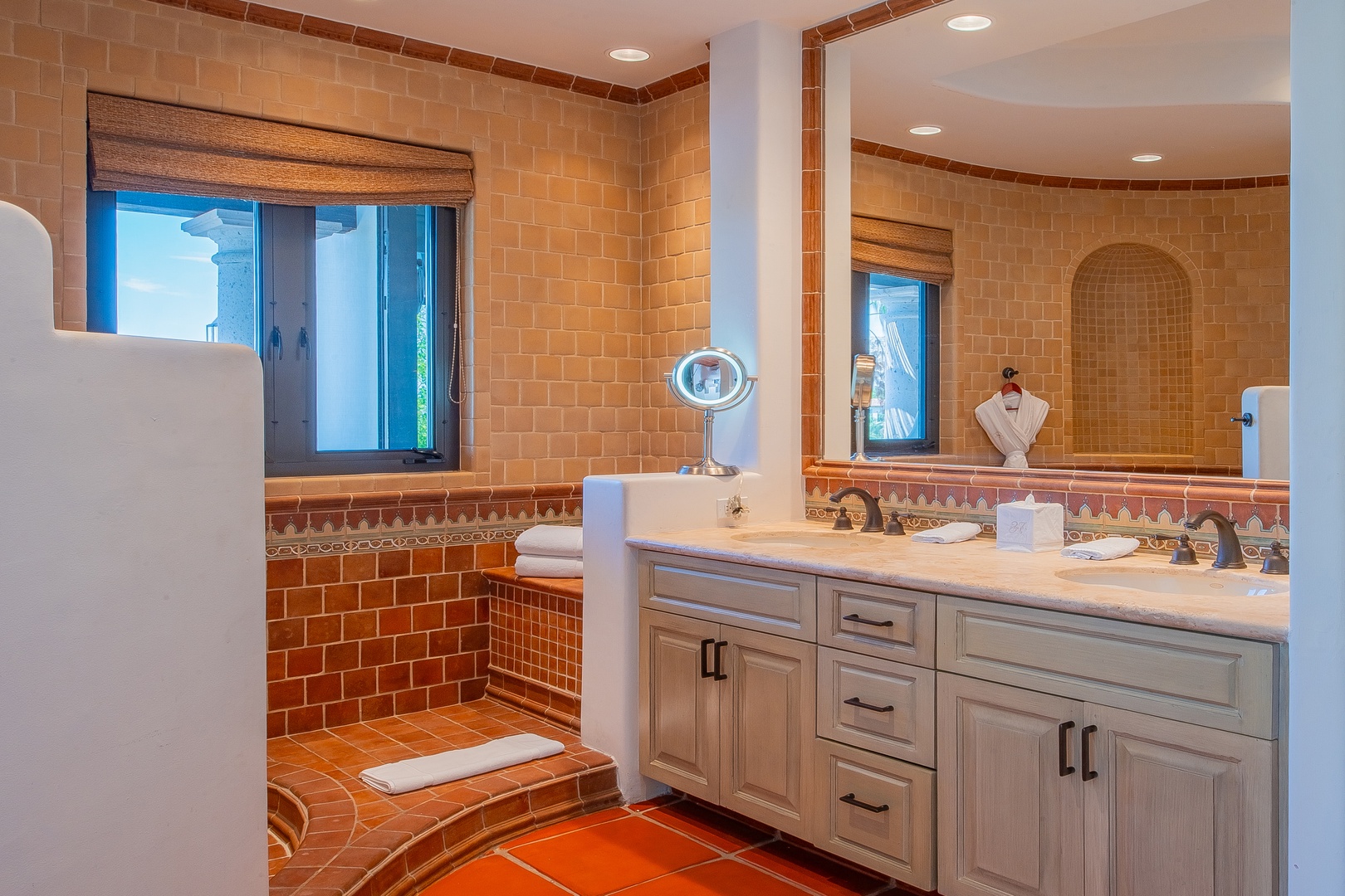Unwind in this beautifully tiled bathroom with warm terracotta tones, dual vanity, walk-in shower, and natural light for your perfect morning routine.