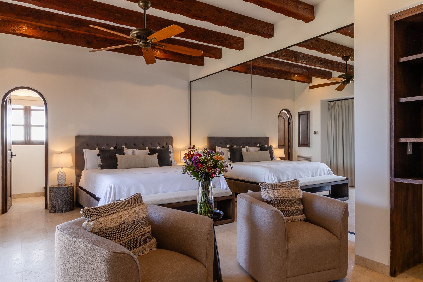Unwind in your spacious suite with rustic wooden beams overhead, plush bedding, and a cozy seating area—your perfect retreat after a day of adventure.