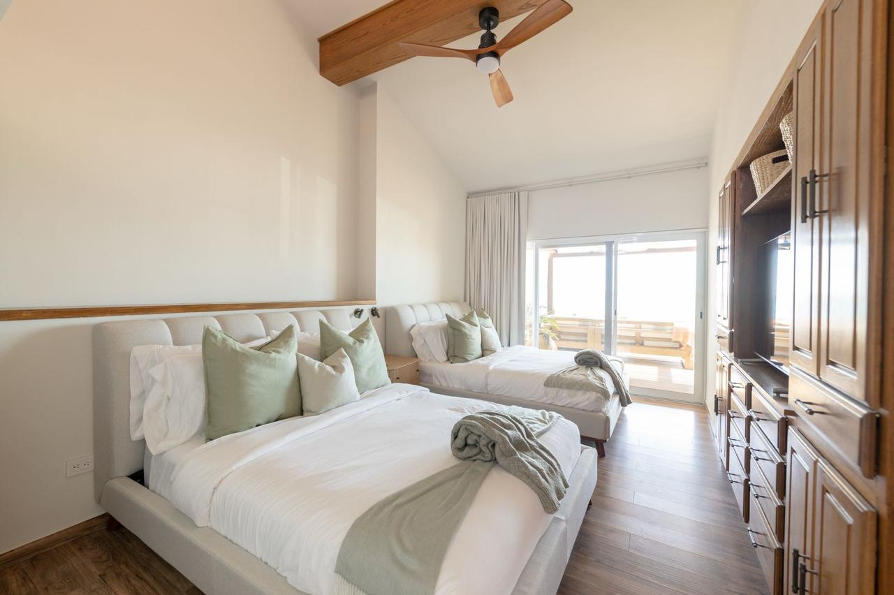 Step into your serene bedroom retreat with two plush beds dressed in crisp linens and sage accents. Natural light floods through sliding doors leading to your private balcony with scenic views.