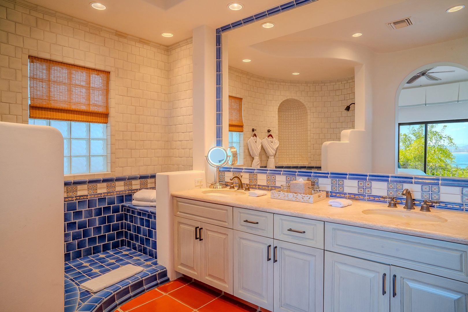 Vibrant blue and white tilework meets soft robes and a soaking tub—your private spa retreat awaits in this beautifully lit bathroom.