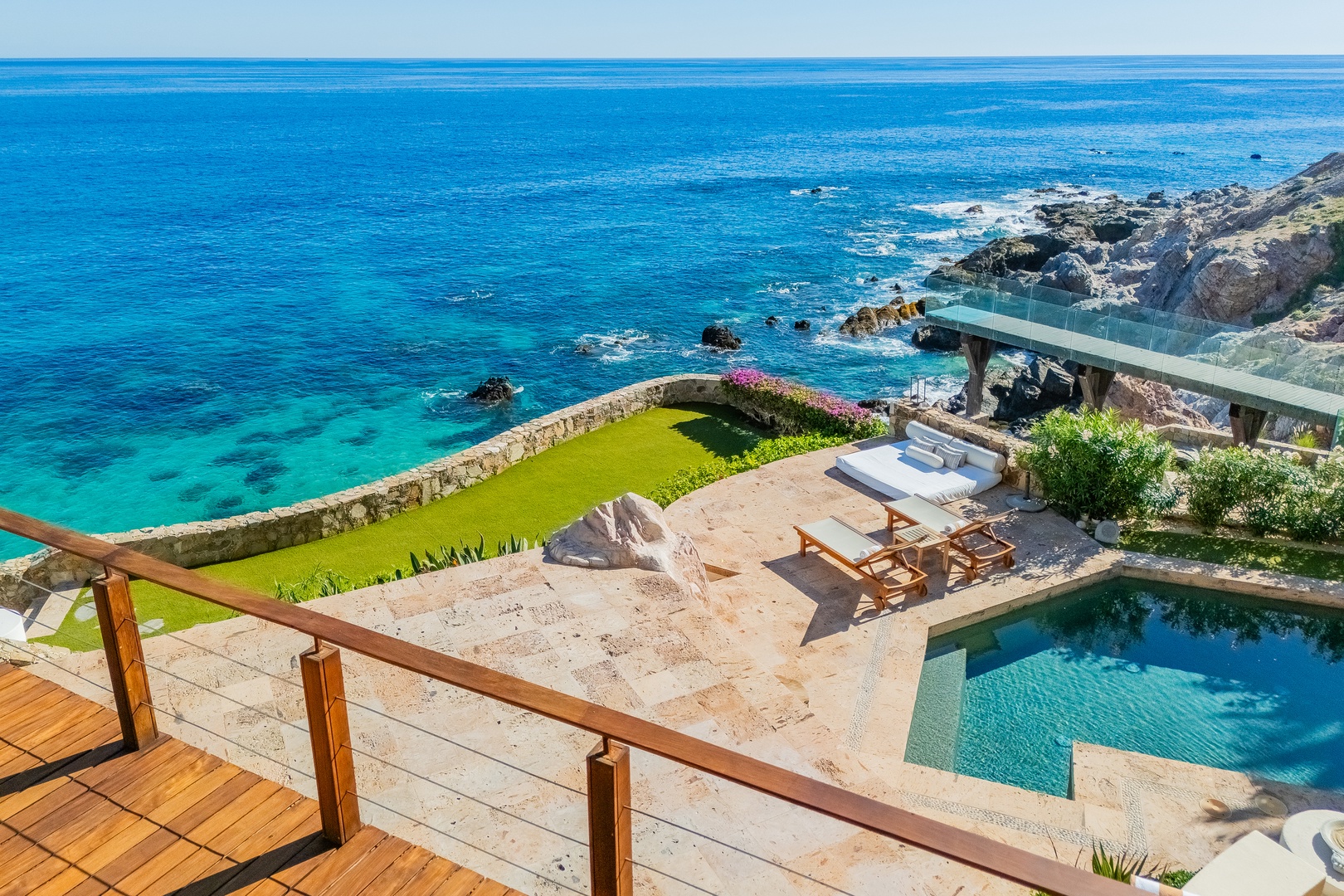 Stunning oceanfront property perched on rocky coastline with private pool, sun terrace, and direct views of turquoise waters stretching to the horizon.