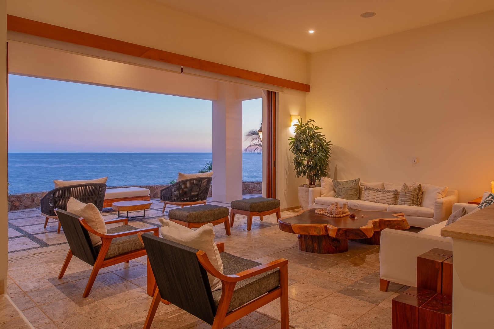 Stunning ocean views frame this serene living space, where you can relax on plush seating surrounded by natural wood accents and gentle coastal light.