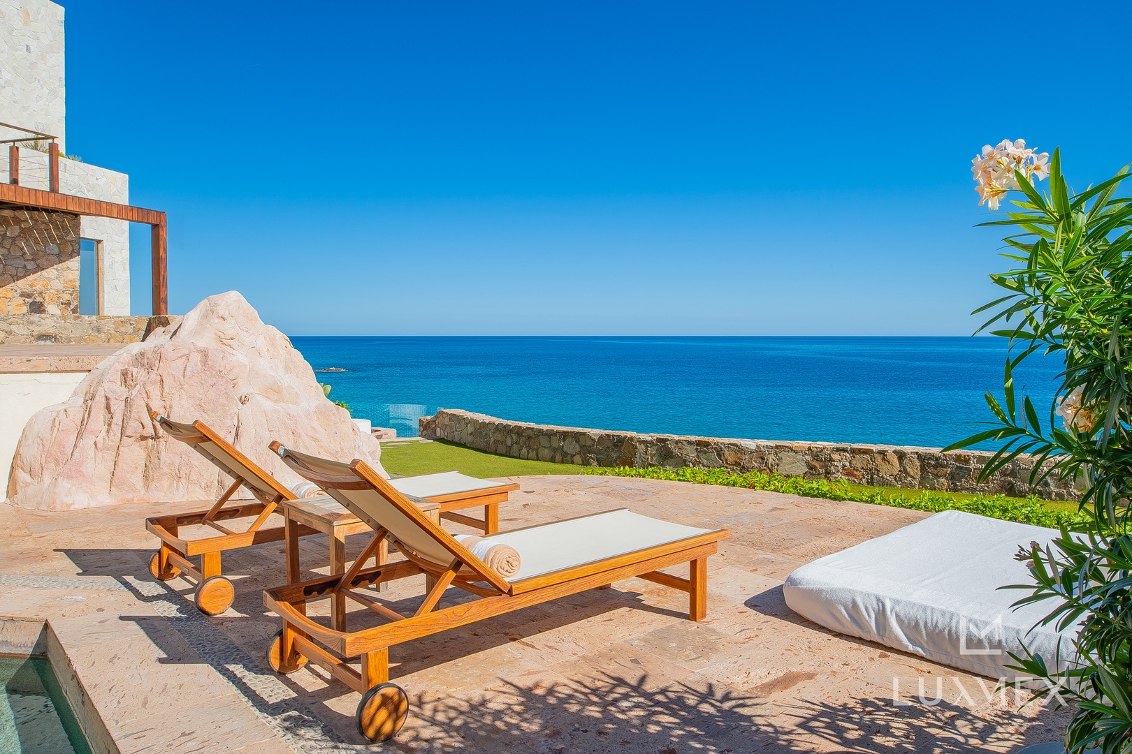 Stunning oceanfront terrace with luxury loungers overlooking endless blue waters - your perfect seaside sanctuary awaits.